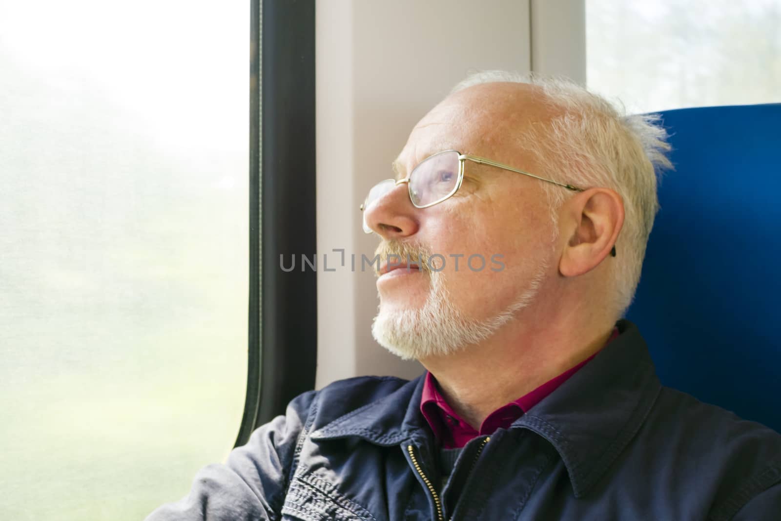 Relaxed old man sitting near the window in the carriage by Tetyana