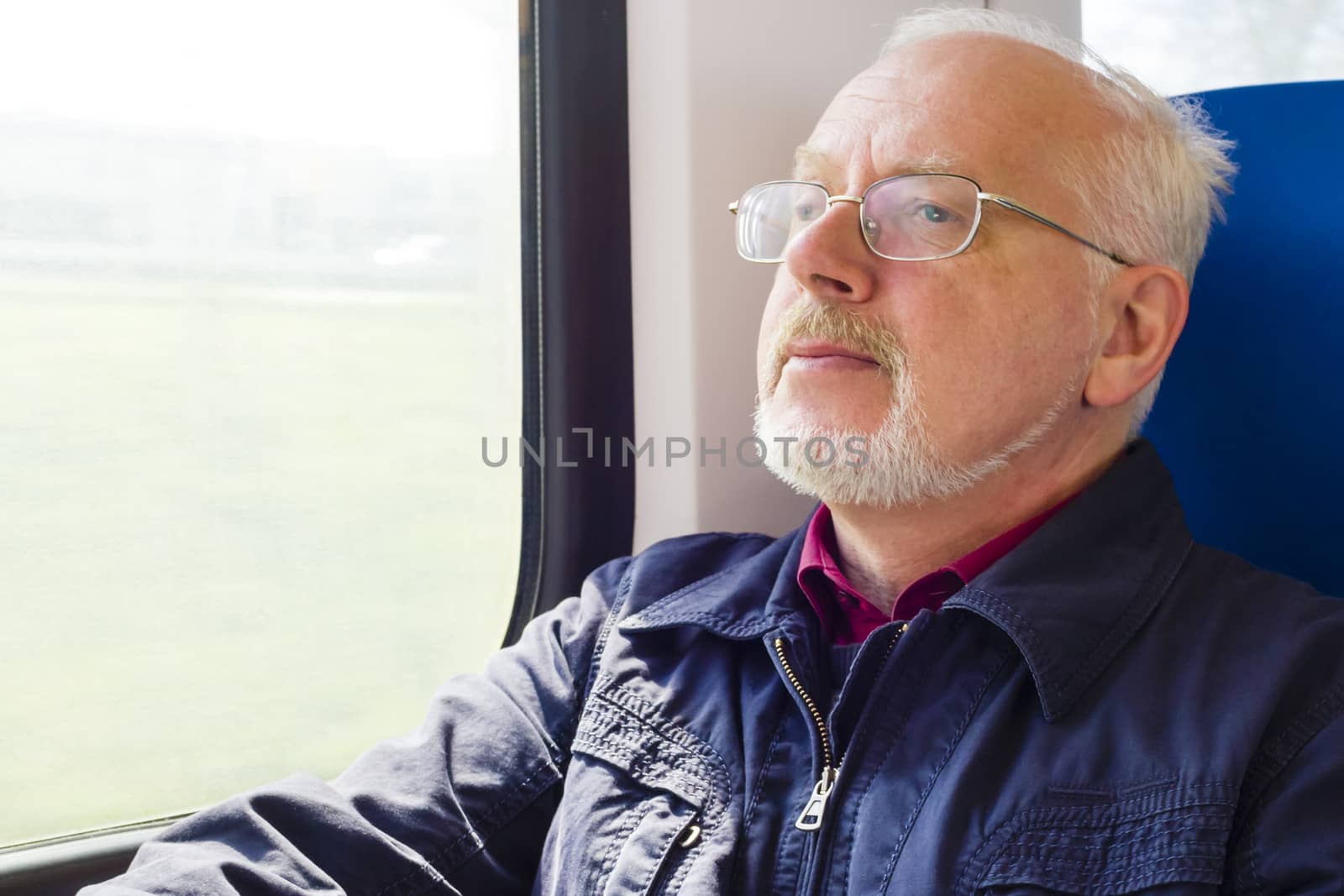 Relaxed old man sitting near the window in the carriage