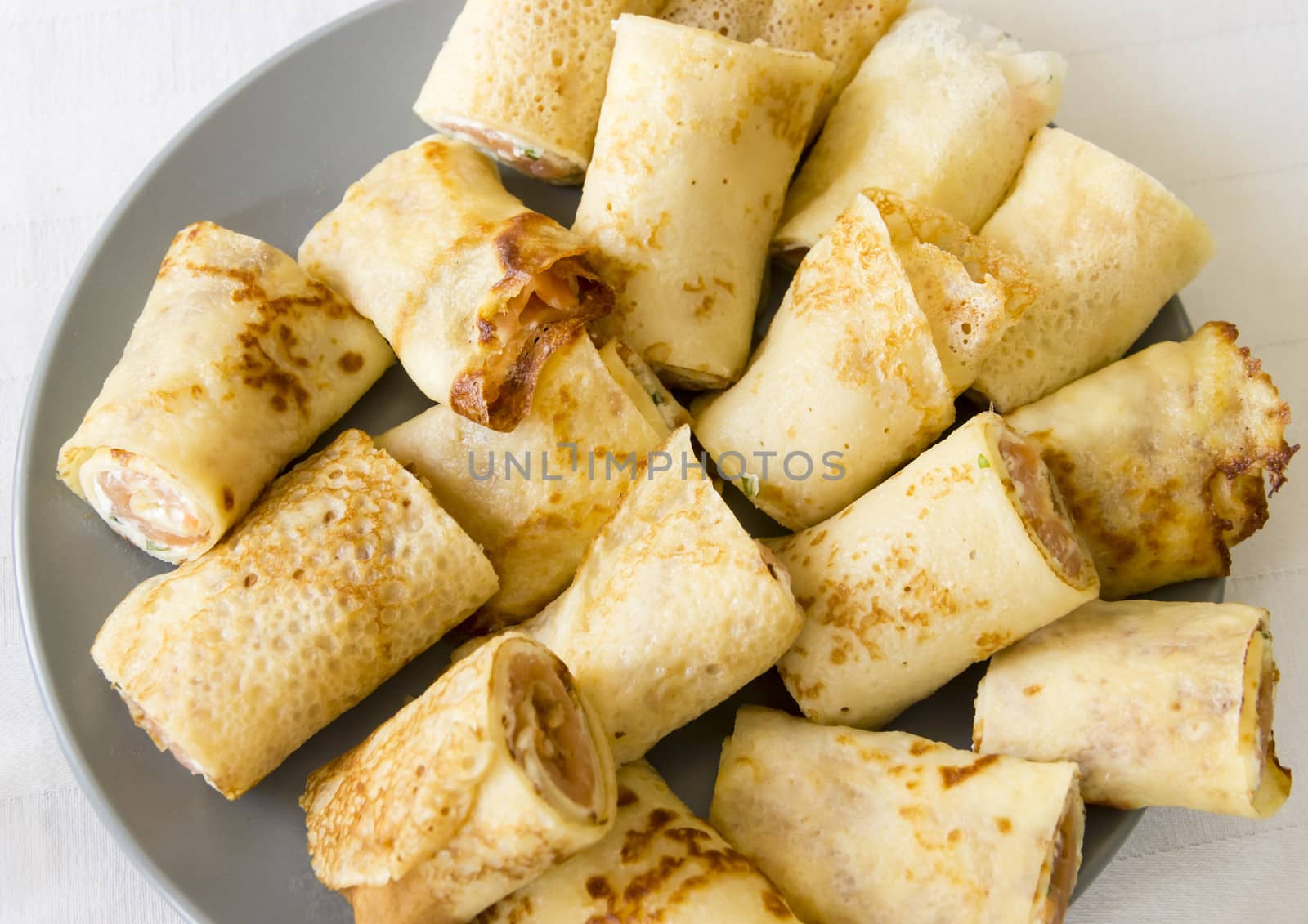 rolled salmon crepe with parsley on a grey plate