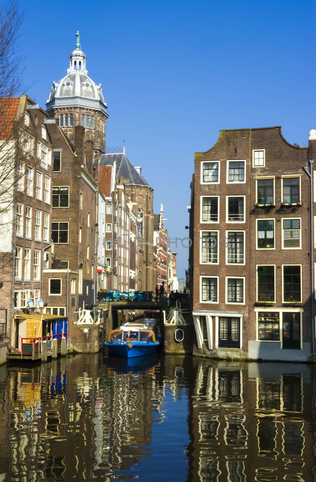 Blue boat on channel in Amsterdam. Typical Amsterdam architecture. Urban space in the spring.