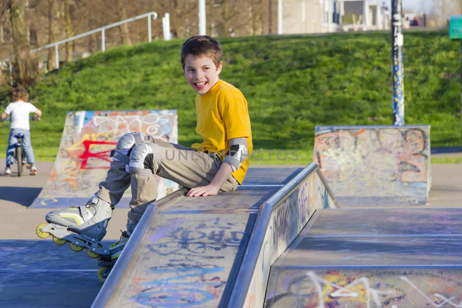 smiling teenage boy in roller-blading protection kit in a skate park