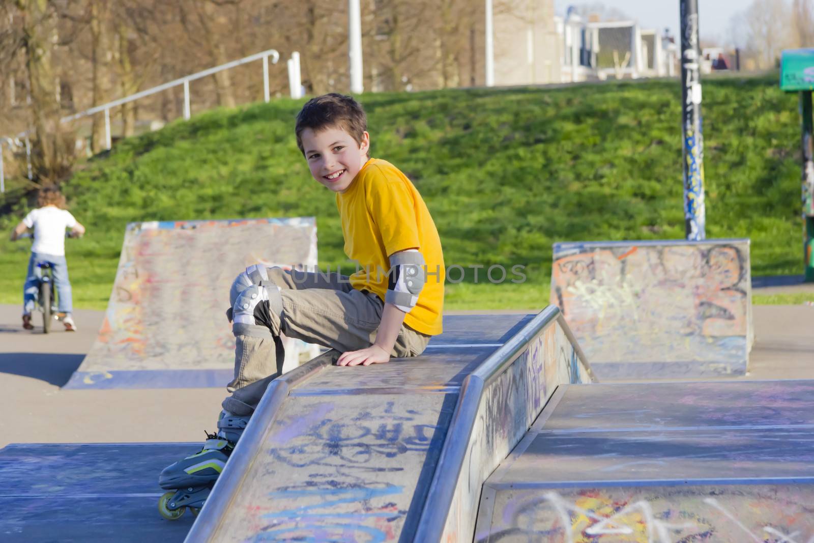 smiling teenage boy in roller-blading protection kit in a skate park