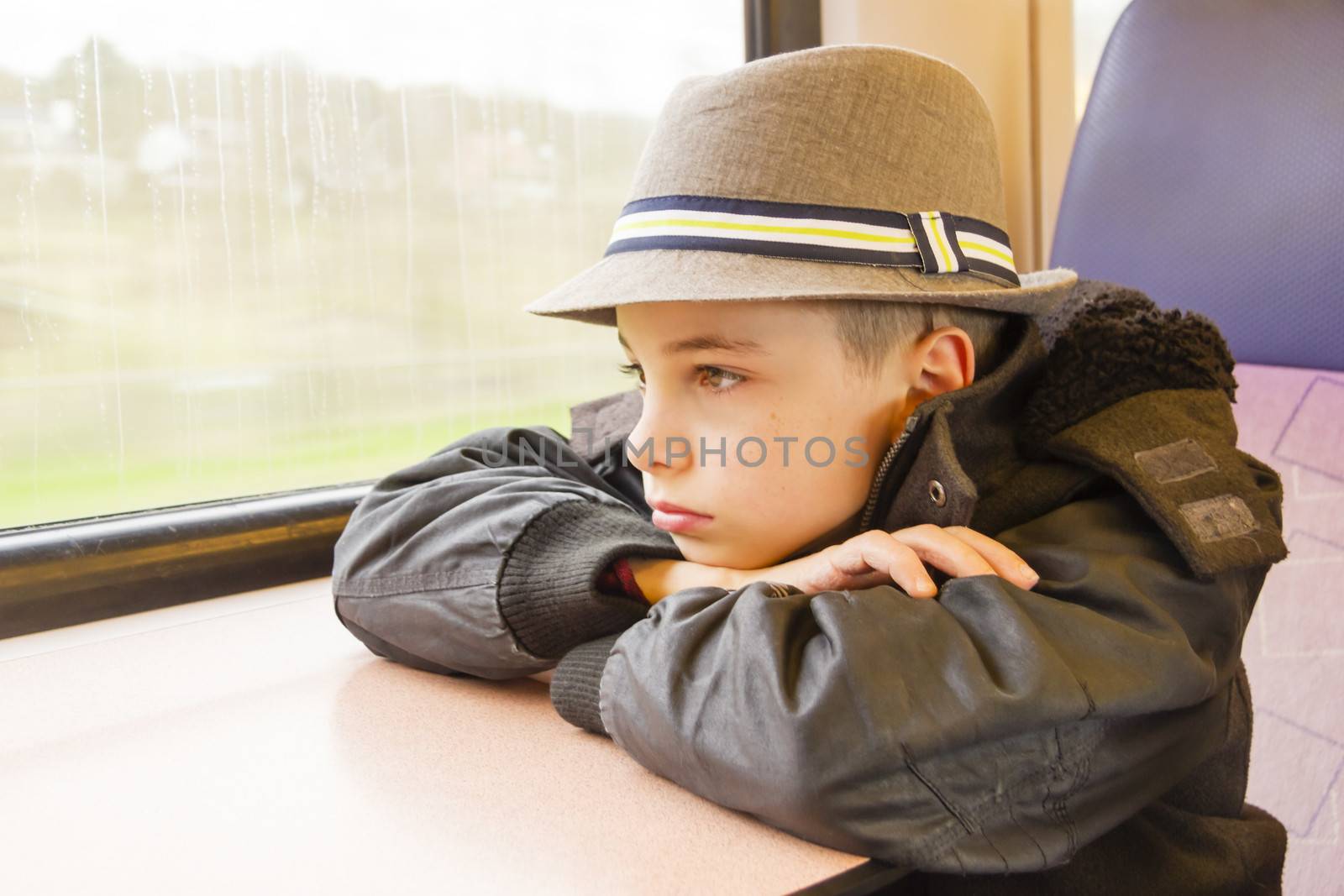 Boy rides on a train and looking out the window. by Tetyana