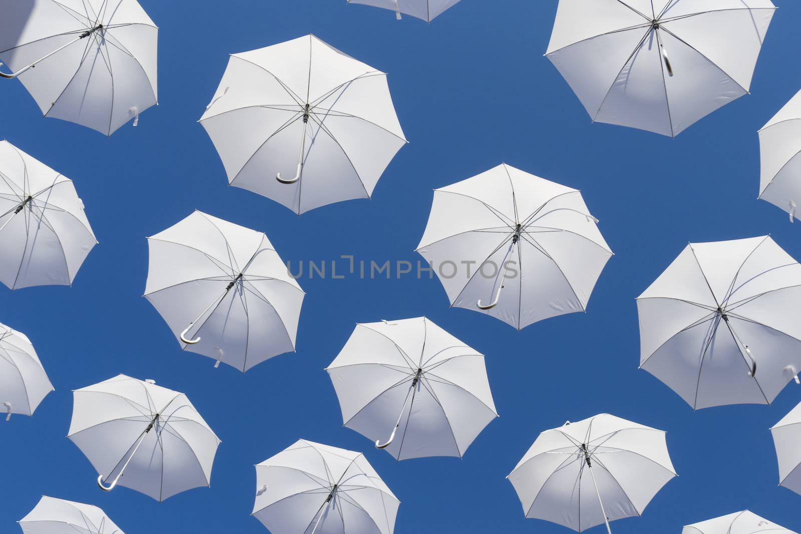 Ornamental white umbrellas flying in the blue sky