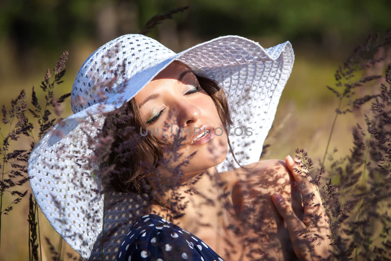 Young woman in white hat on natural background with grass