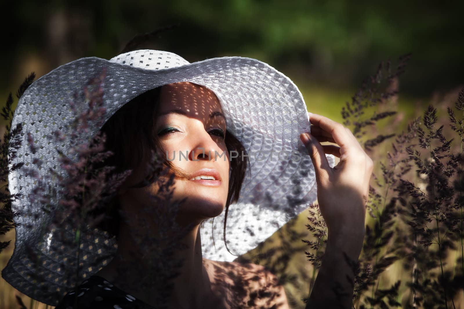 Young woman in white hat on natural background with grass