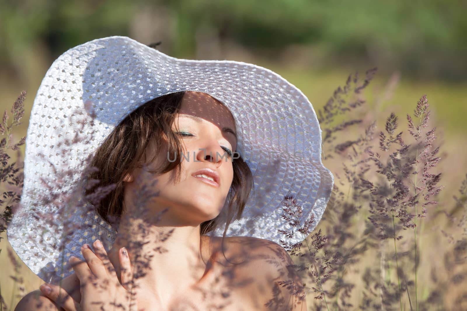 Young woman in white hat on natural background with grass