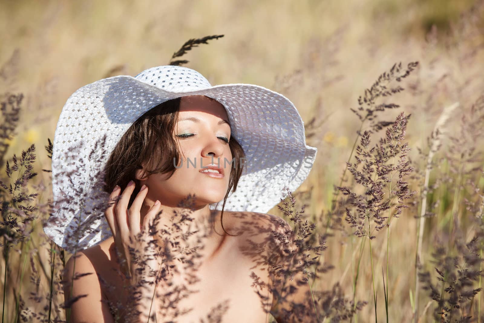 Young woman in white hat on natural background with grass