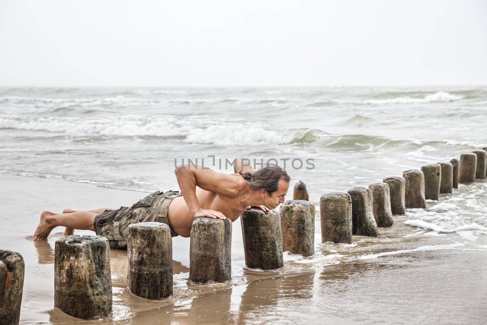 Middle-aged man doing pushups on the beach