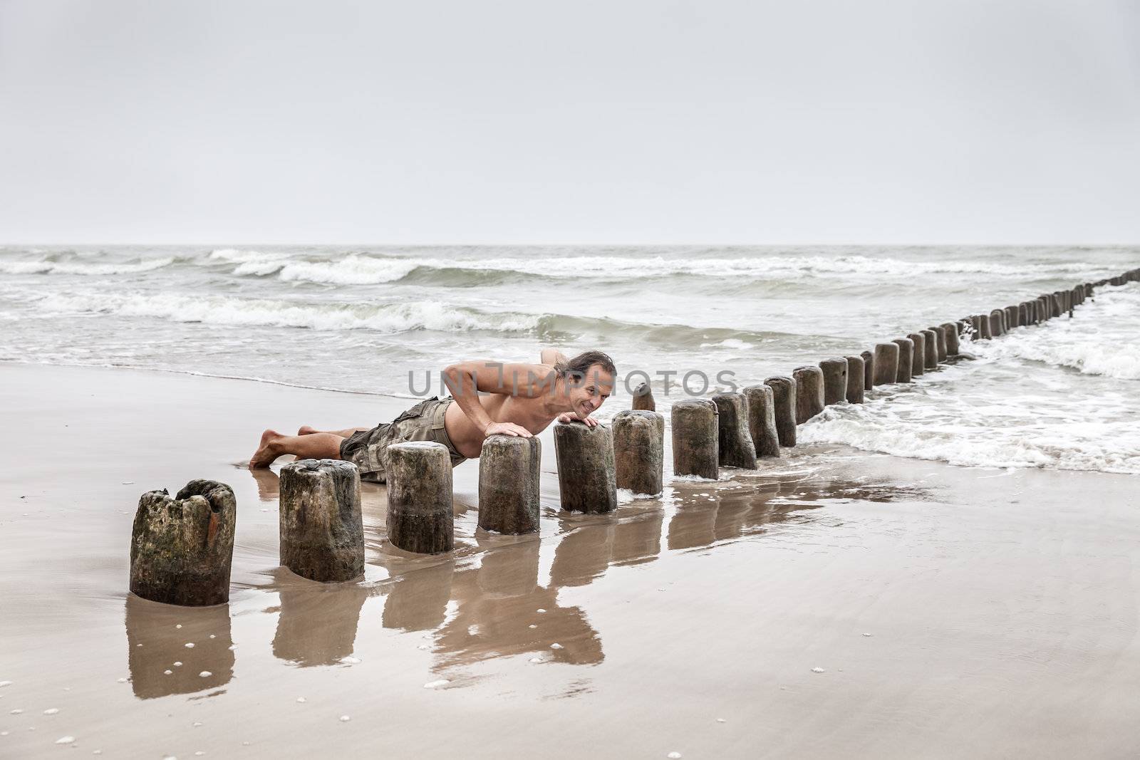 Middle-aged man doing pushups on the beach