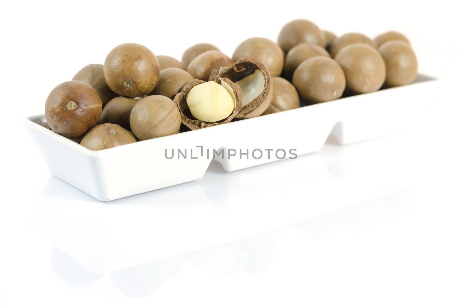 close up macadamia in  white bowl  on white background with reflection
