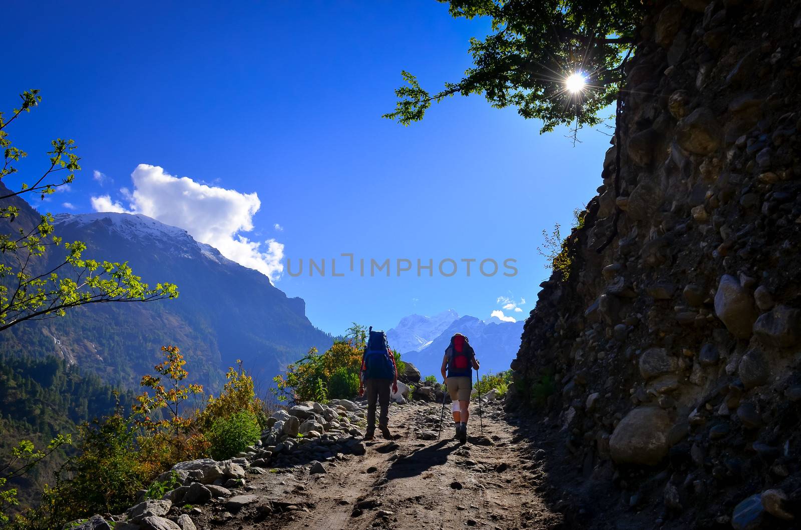 Two people trekking the the mountains during sunny day by martinm303