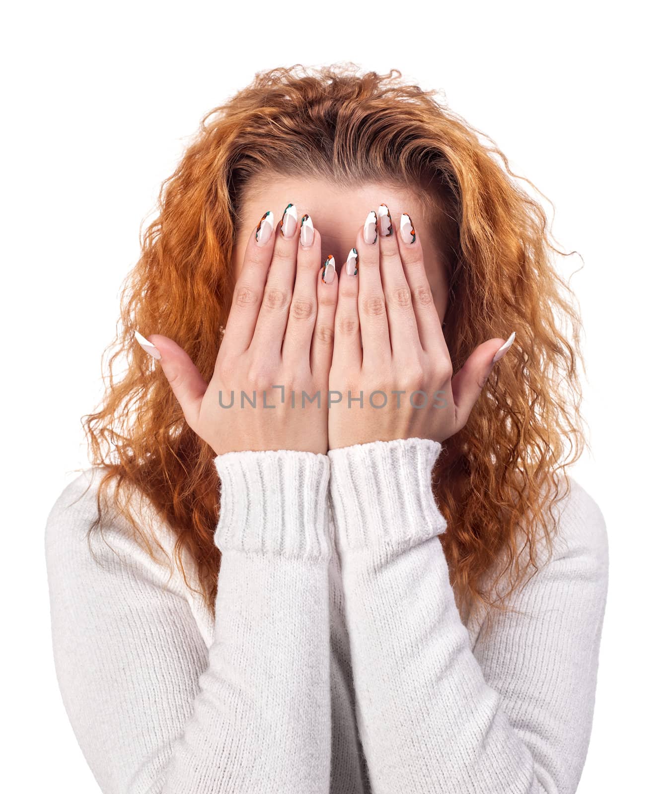 Portrait of red-haired woman covering her face by the hands, over white background