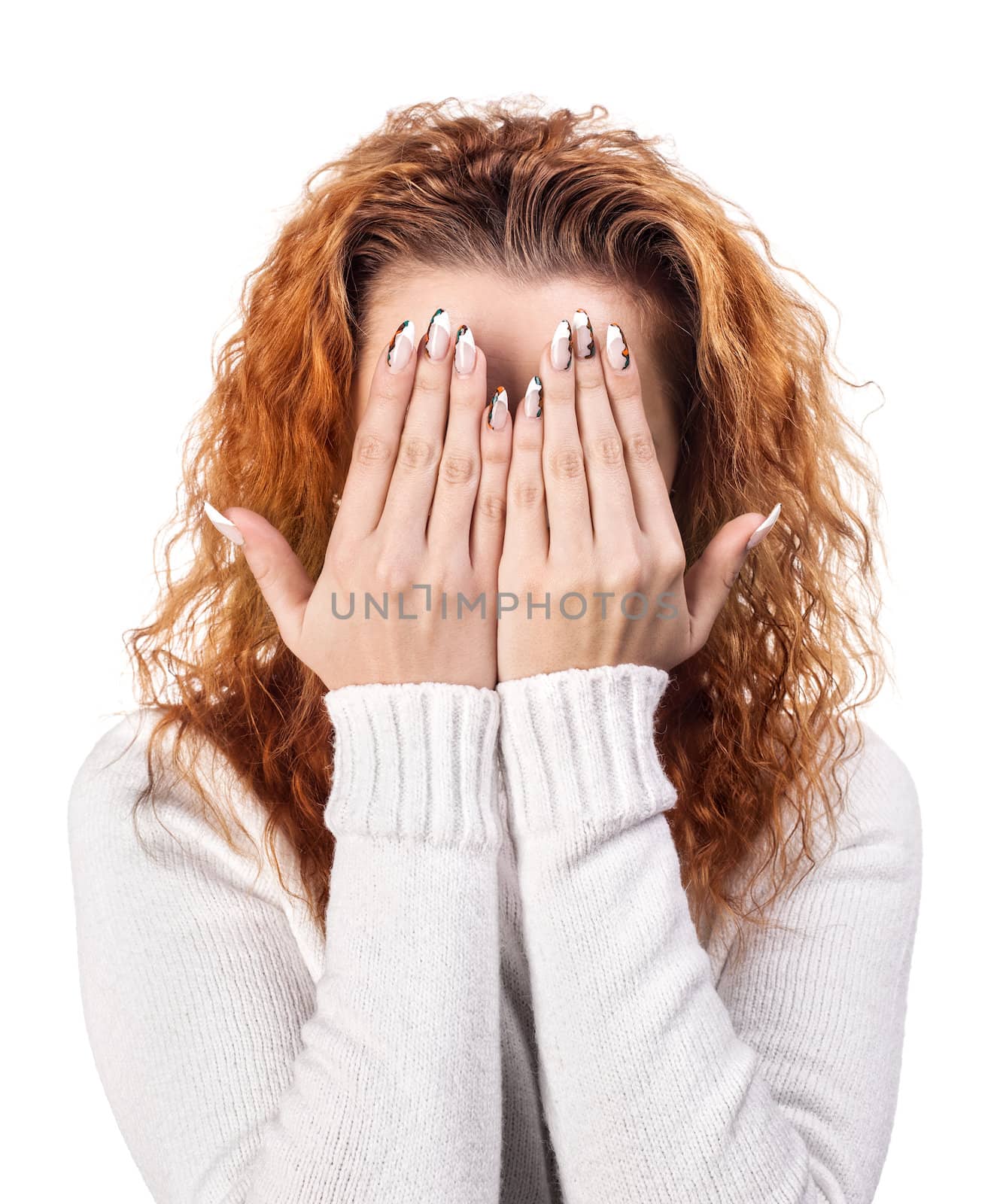 Portrait of red-haired woman covering her face by the hands, over white background