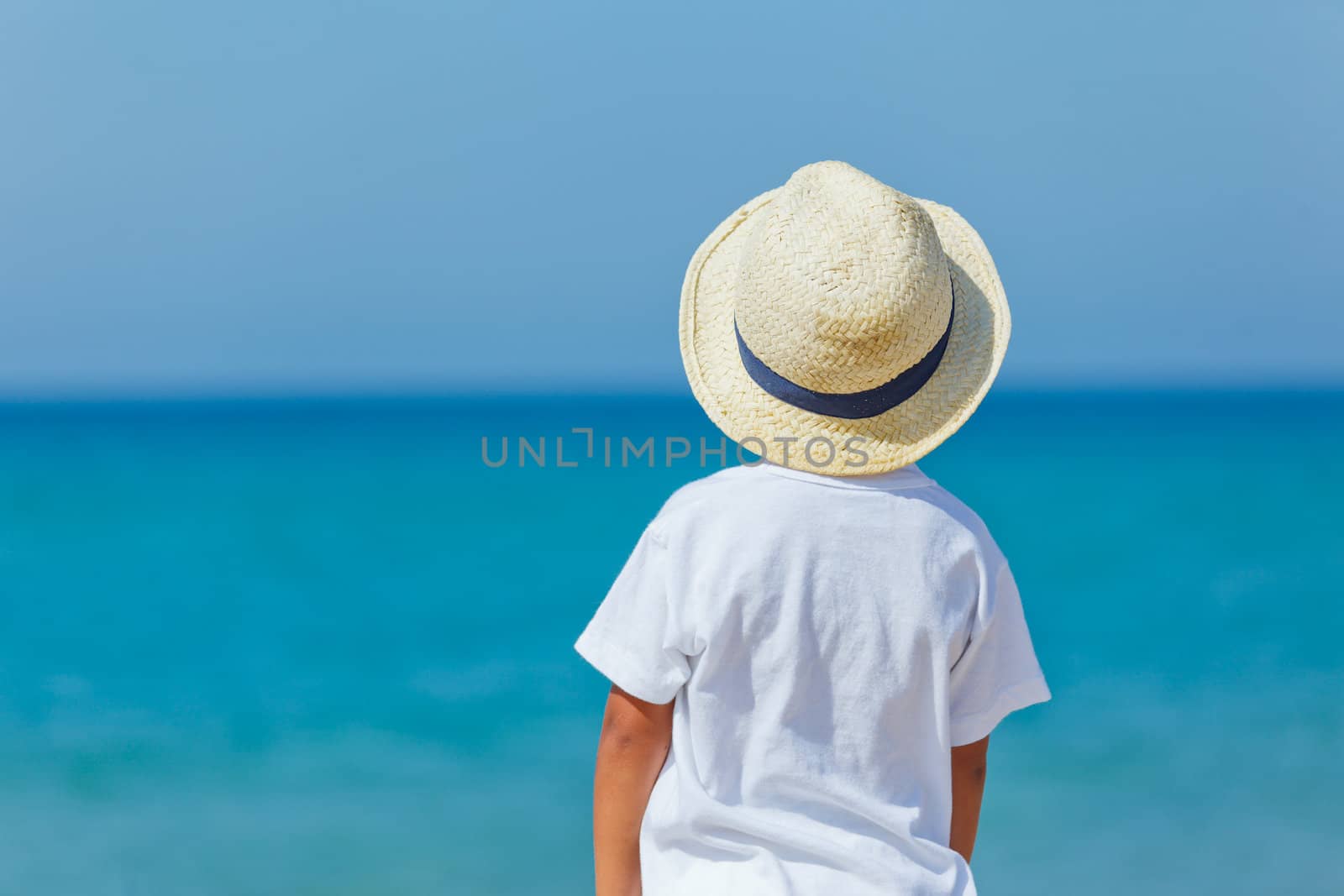 Smiling cute boy with a sun hat at the tropical beach.