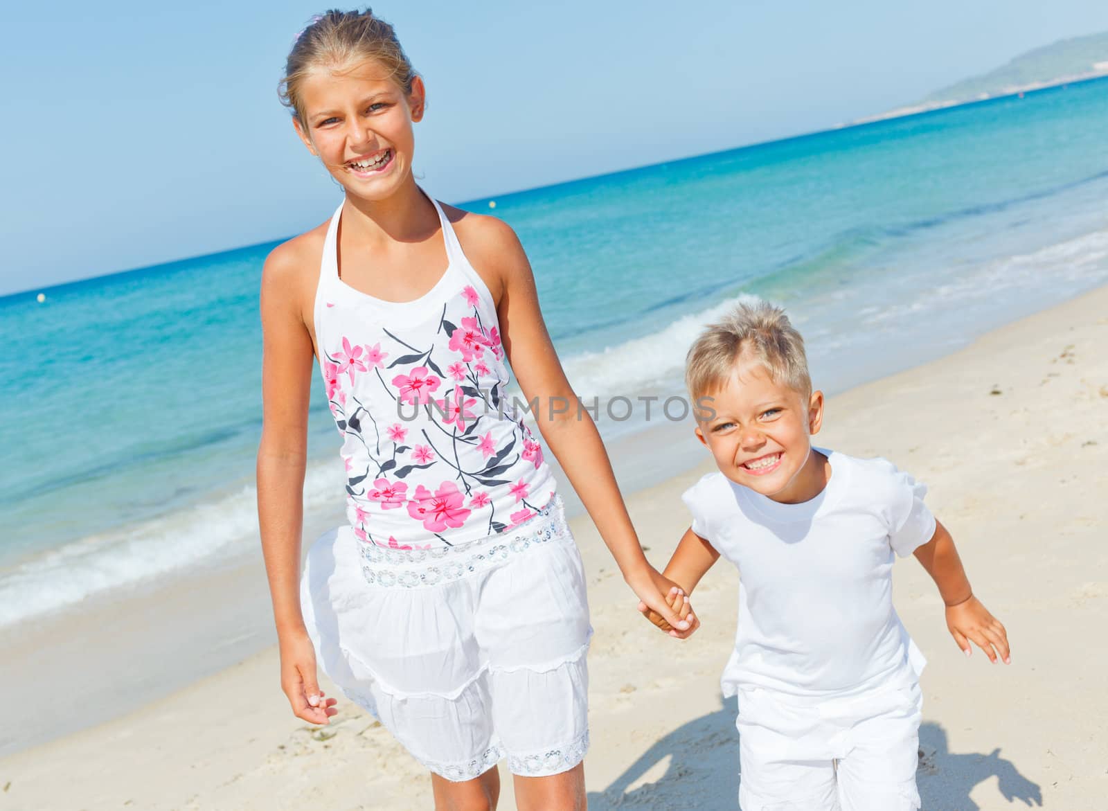 Adorable happy boy and girl running on beach vacation