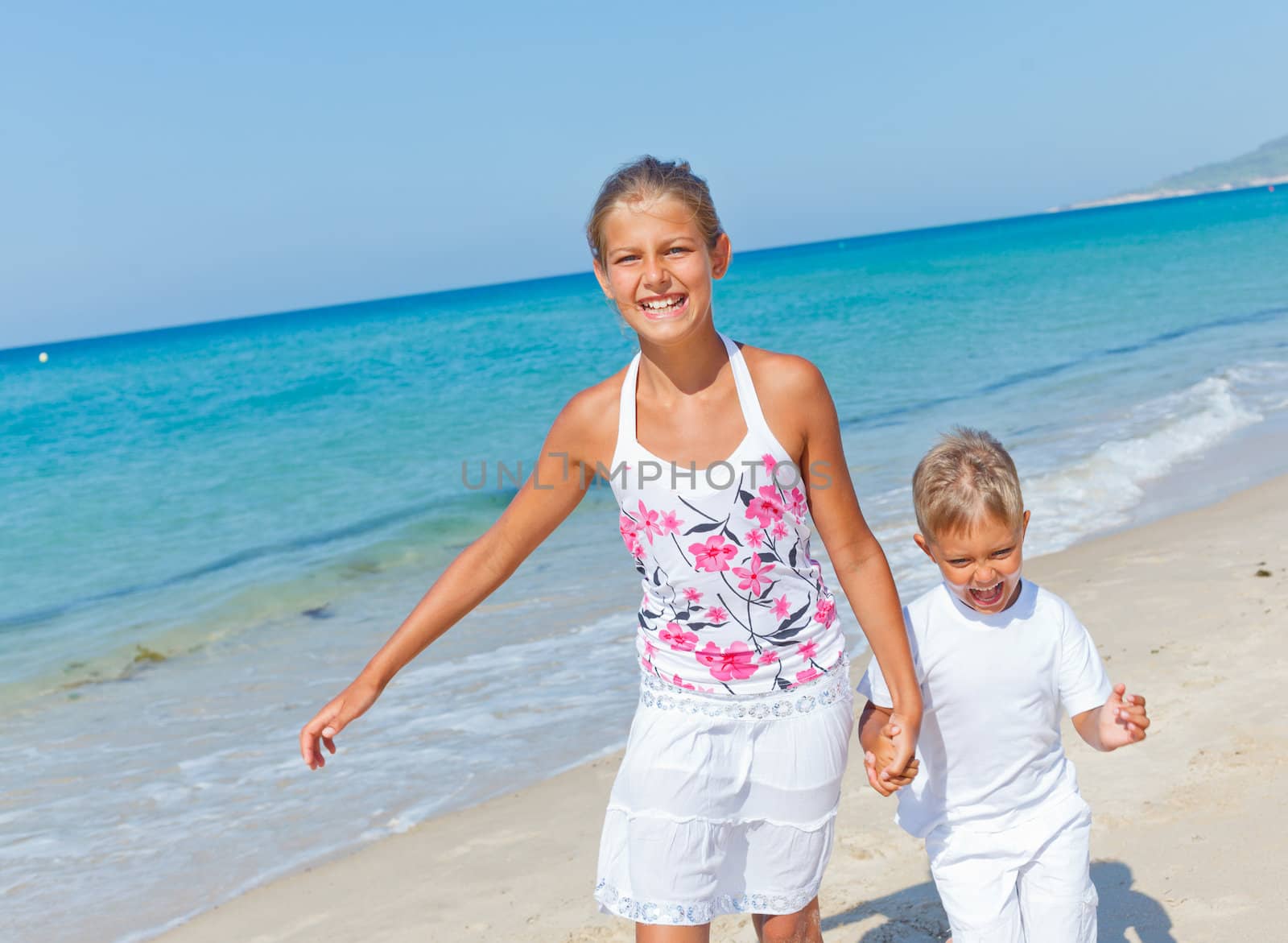 Adorable happy boy and girl running on beach vacation