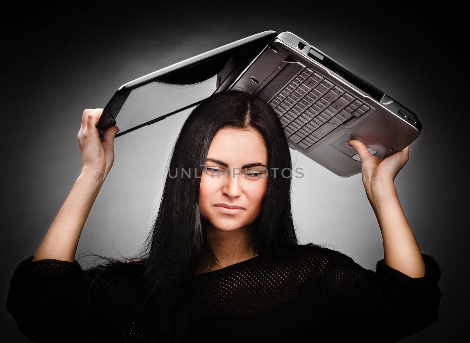 Stressed young woman with a laptop on her head