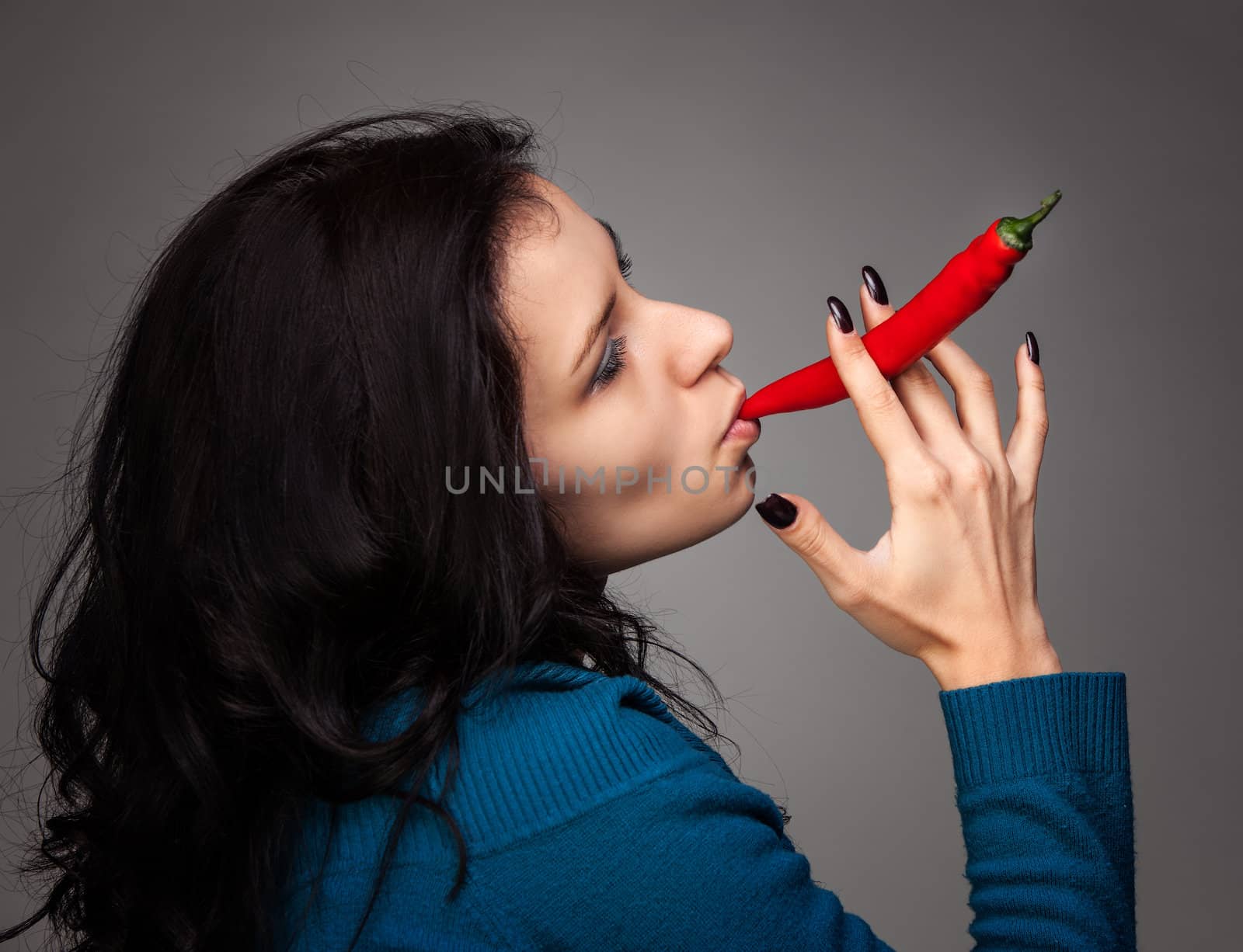 woman holding red hot chili pepper in mouth by palinchak