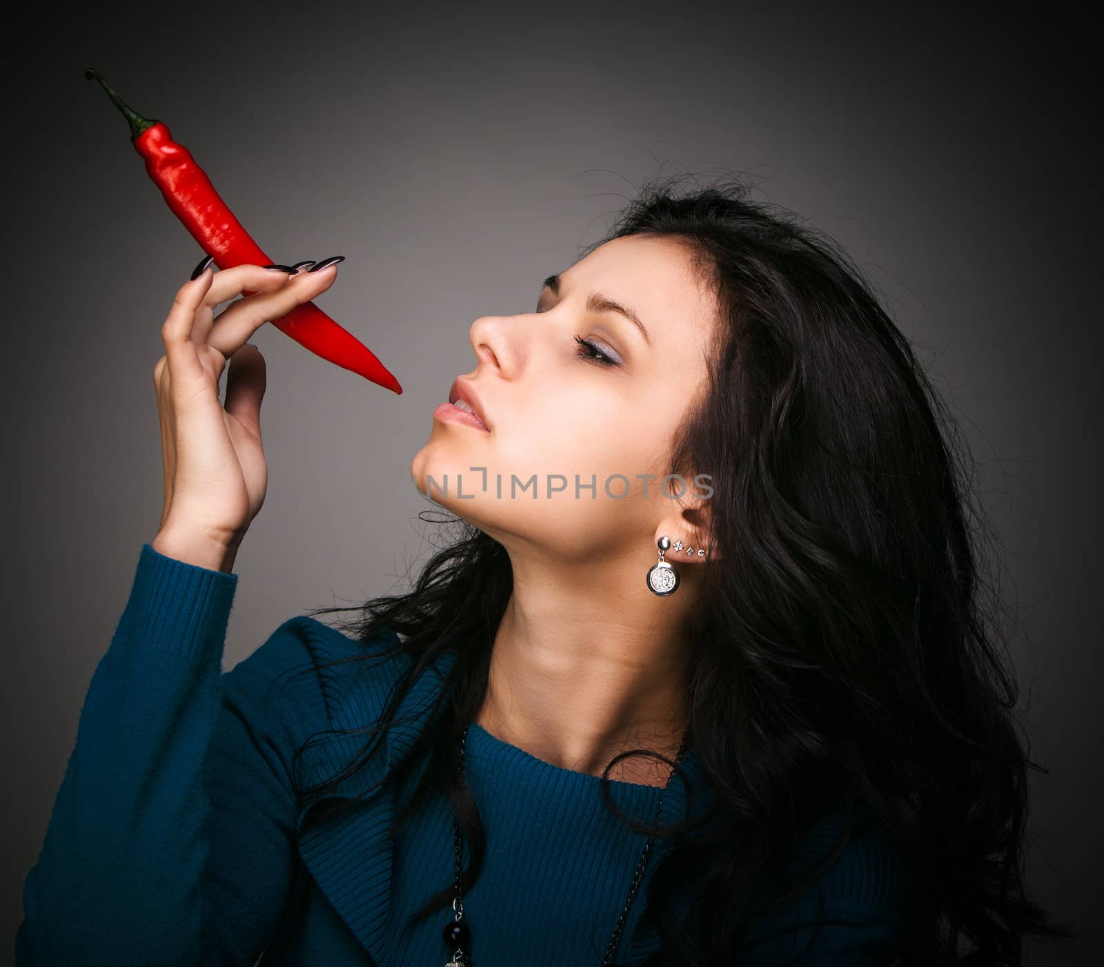 woman holding red hot chili pepper in mouth by palinchak