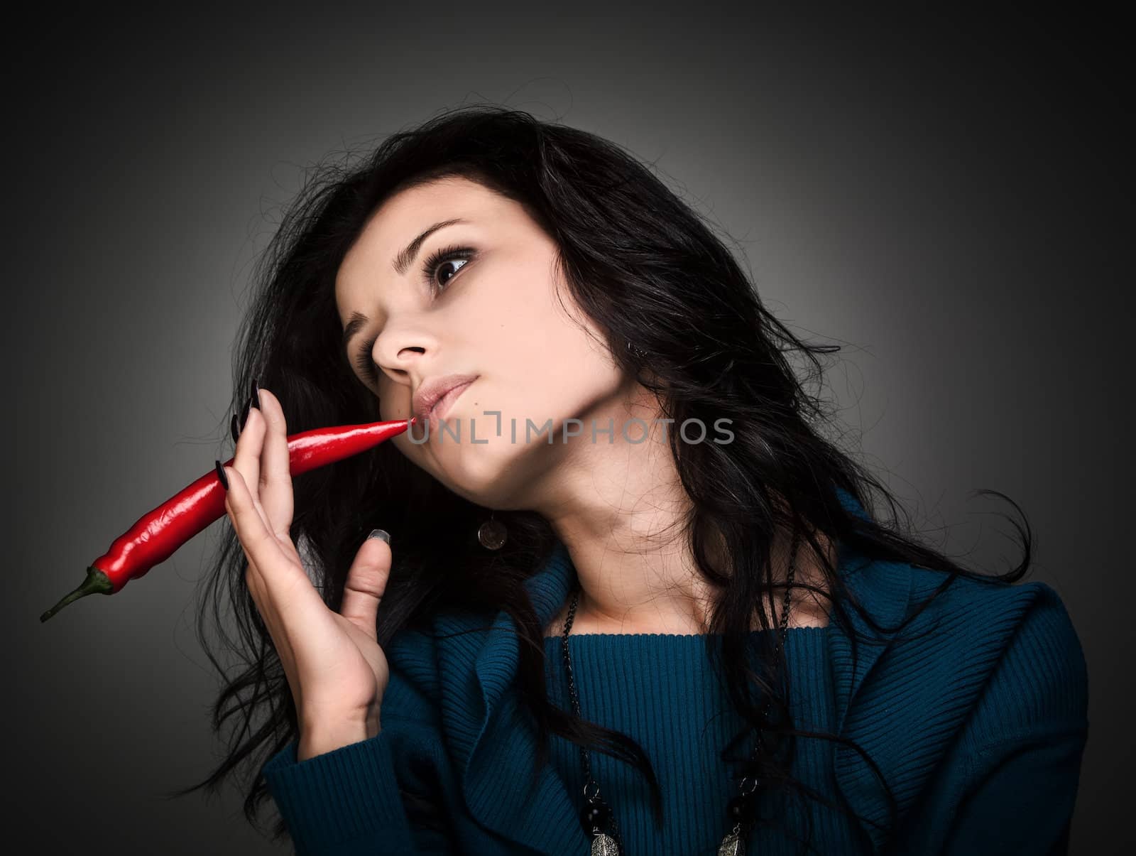 woman holding red hot chili pepper in mouth by palinchak