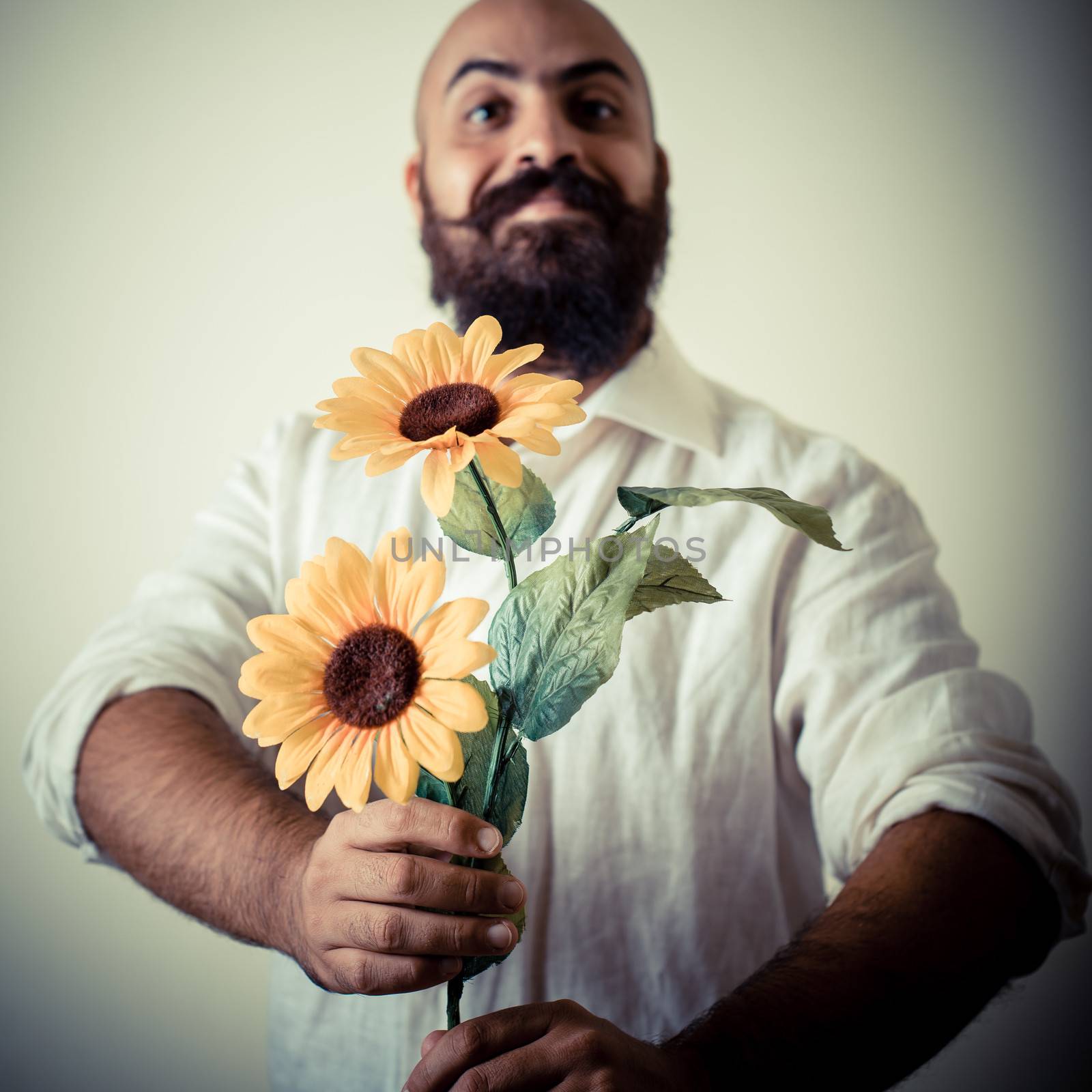 long beard and mustache man giving flowers on gray background