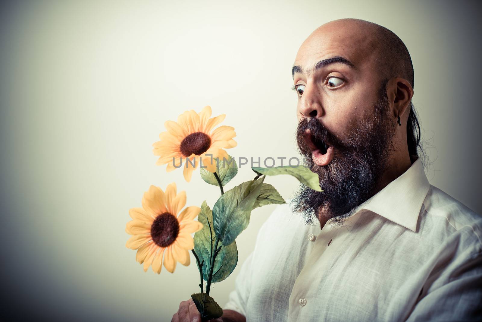 long beard and mustache man giving flowers on gray background