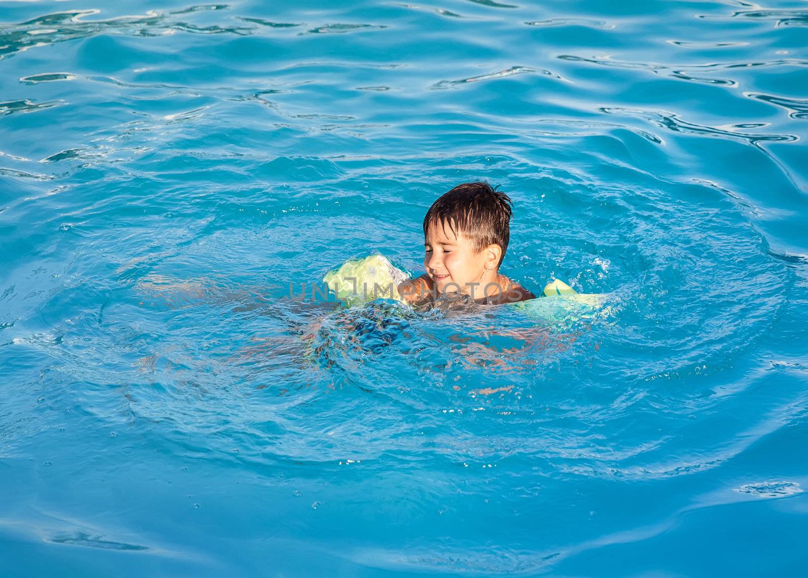 Little boy learning to swim in the pool 