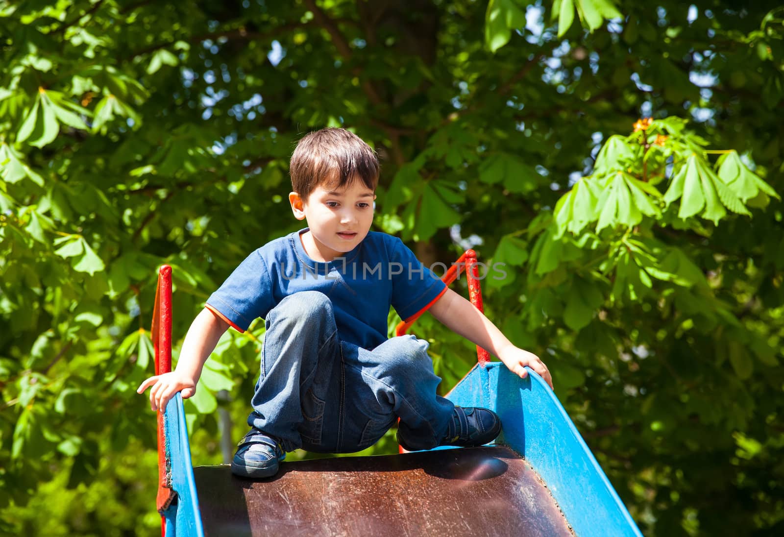 Cute boy playing on slide by palinchak