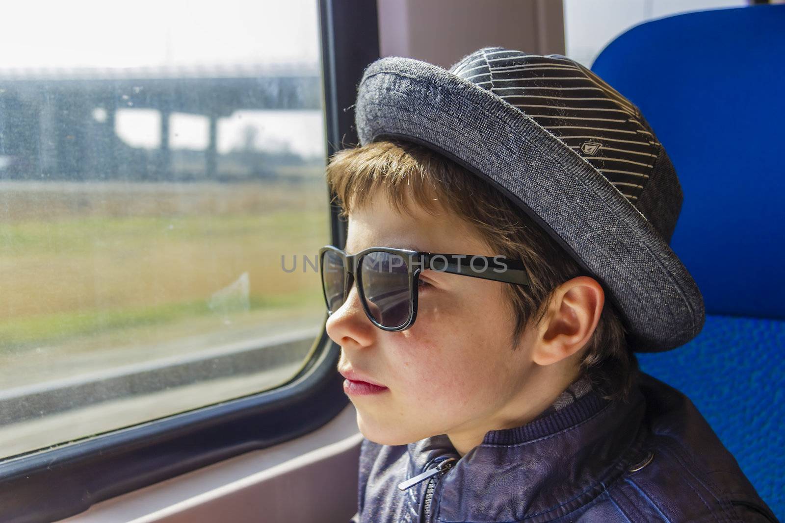 Handsome boy in sunglasses rides on a train