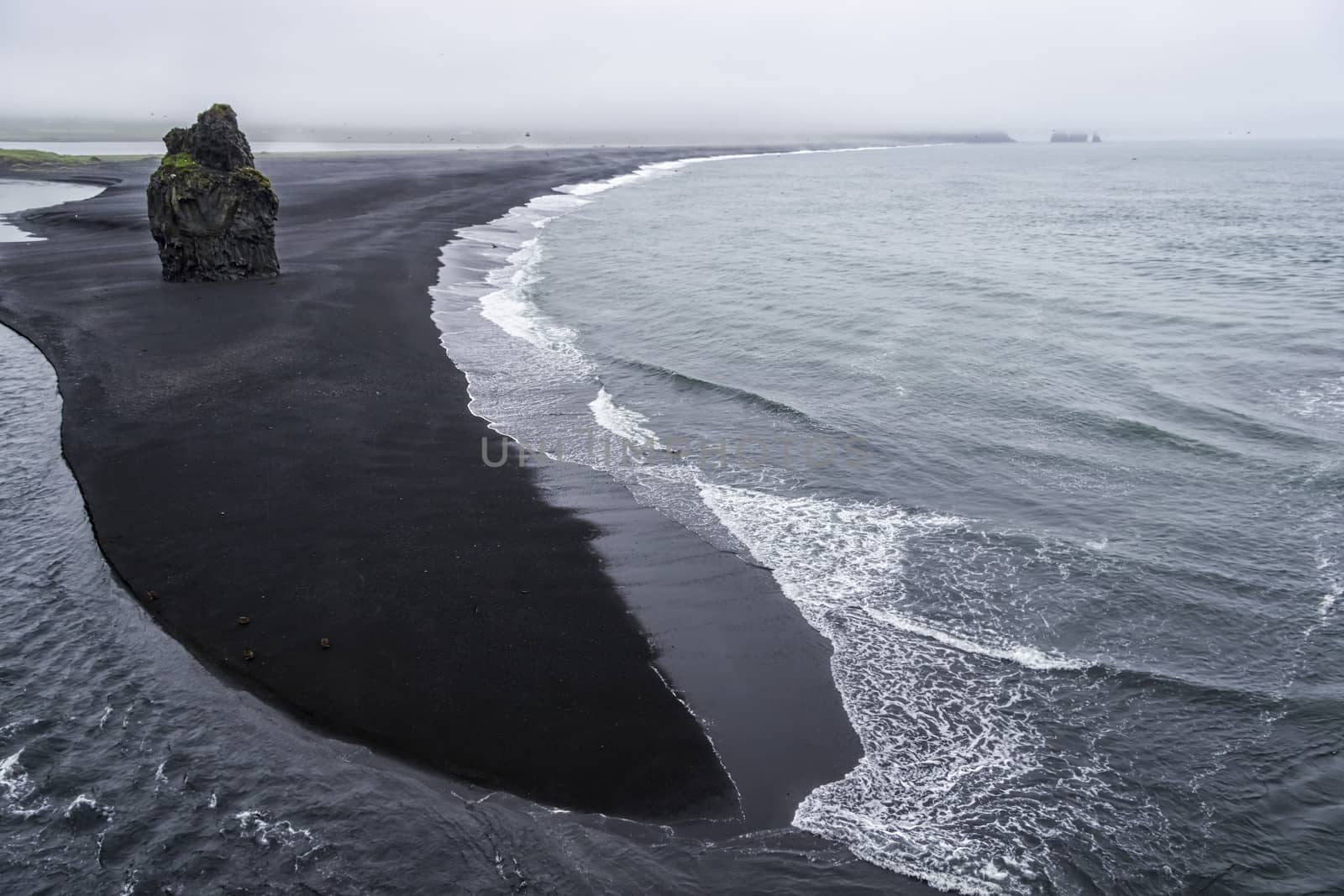 Black volcanic sand on the south coast of Iceland in rainy weath by Tetyana