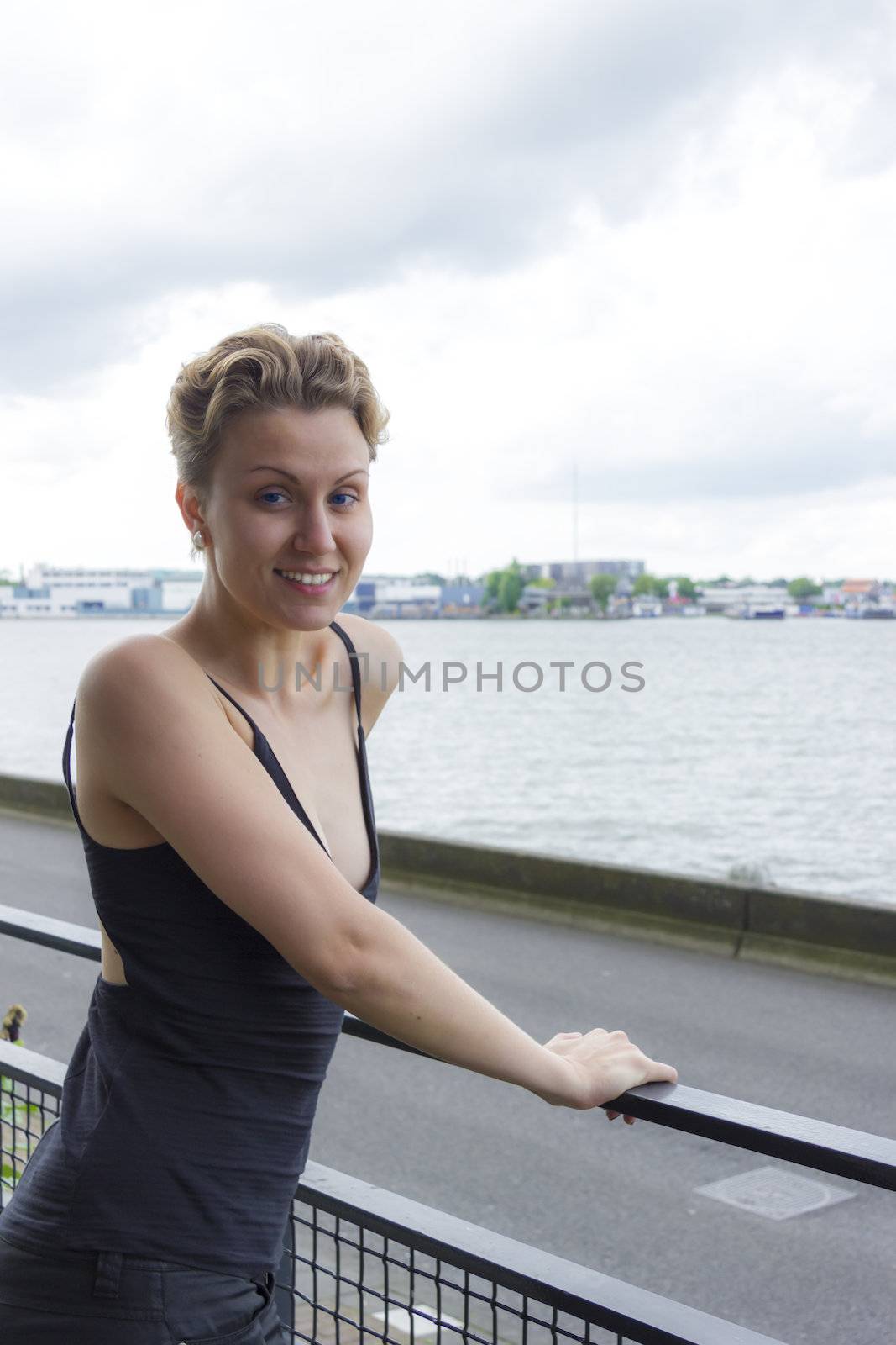 portrait of cute smiling girl with blue eyes against industrial and river background