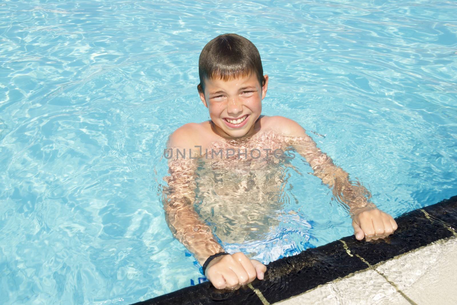Activities on the pool. Cute boy swimming and playing in water in swimming pool by Tetyana