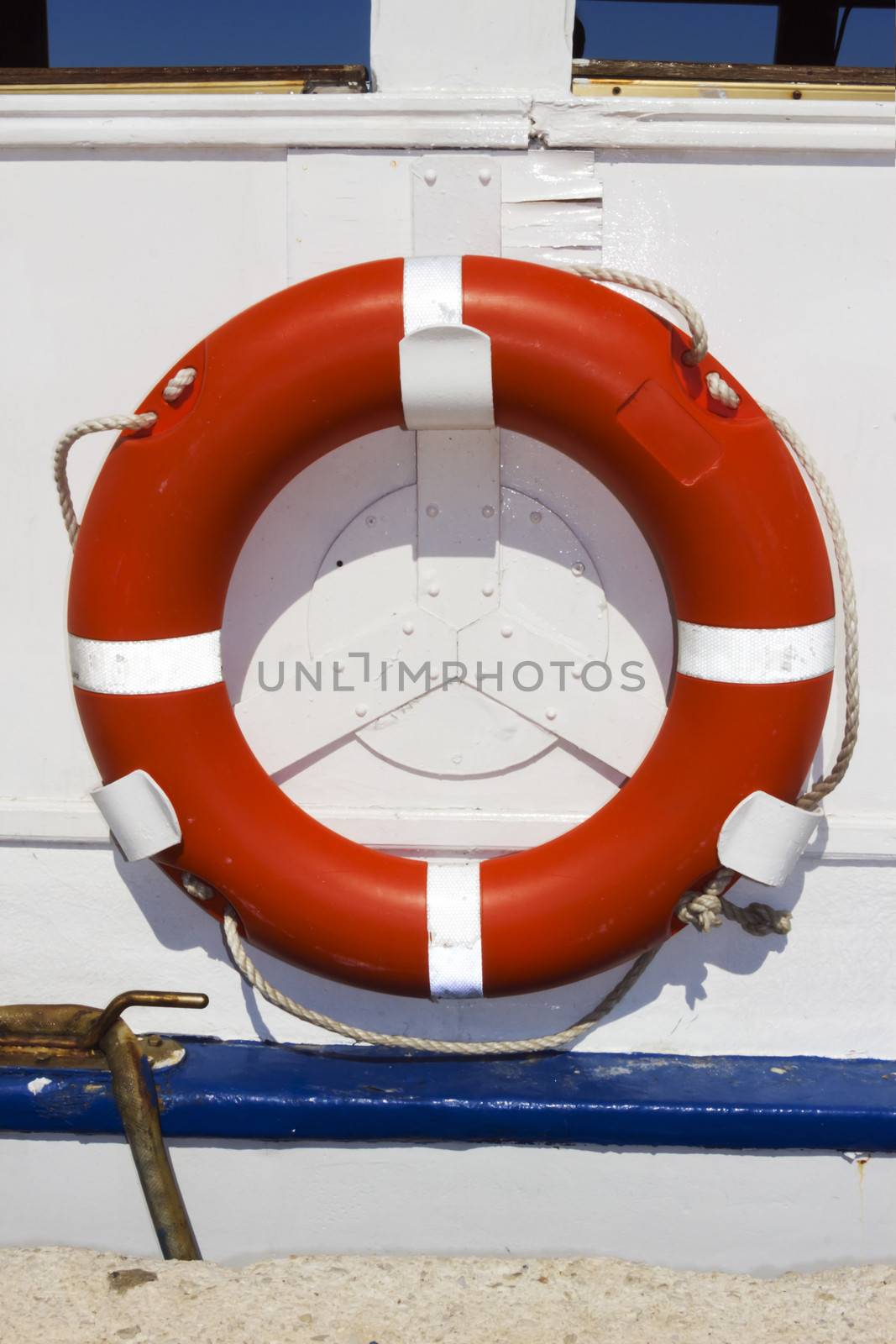 Orange ring buoy hanging on white painted boat by Tetyana