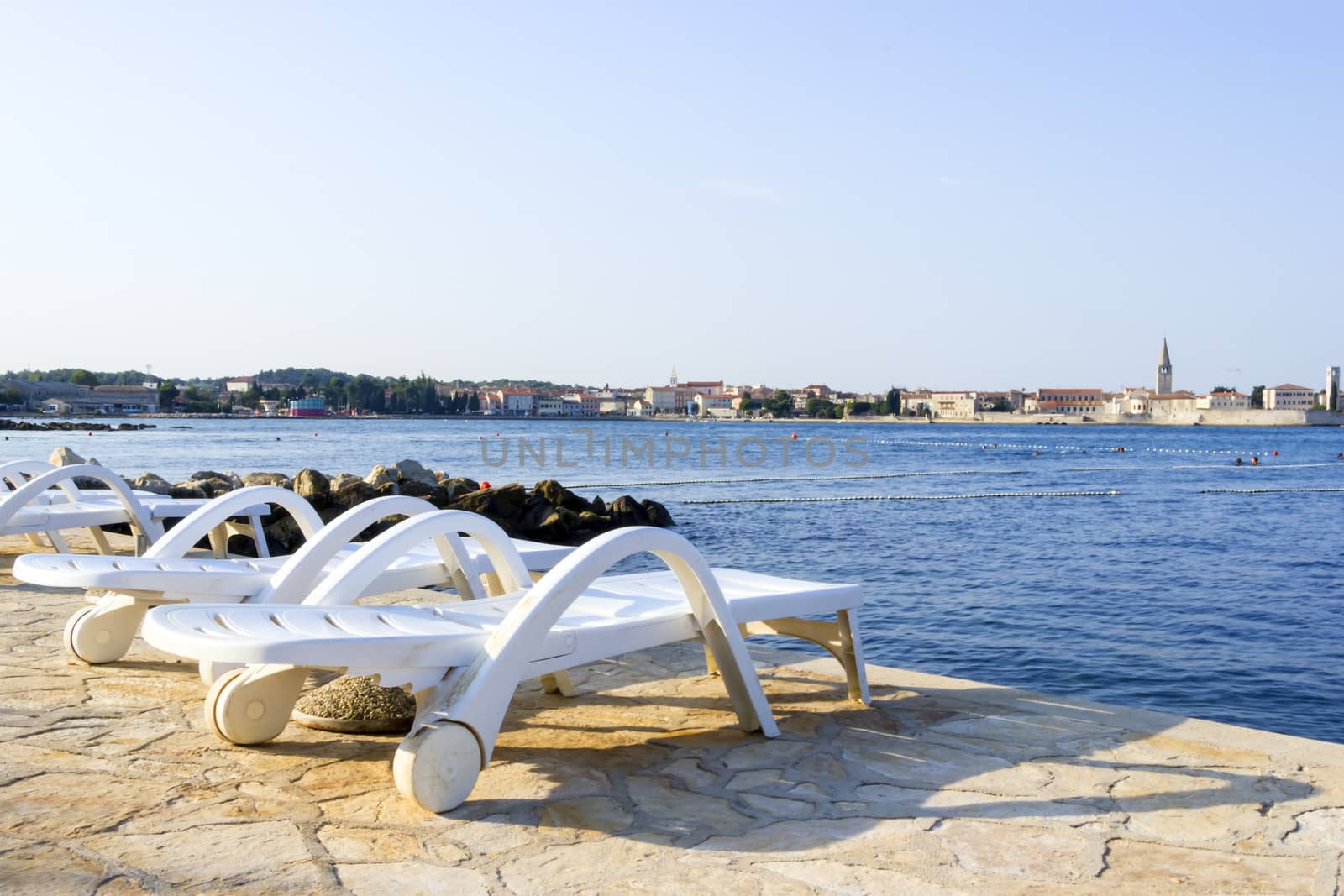 The beach in Porec in the morning, in the light of the rising sun by Tetyana
