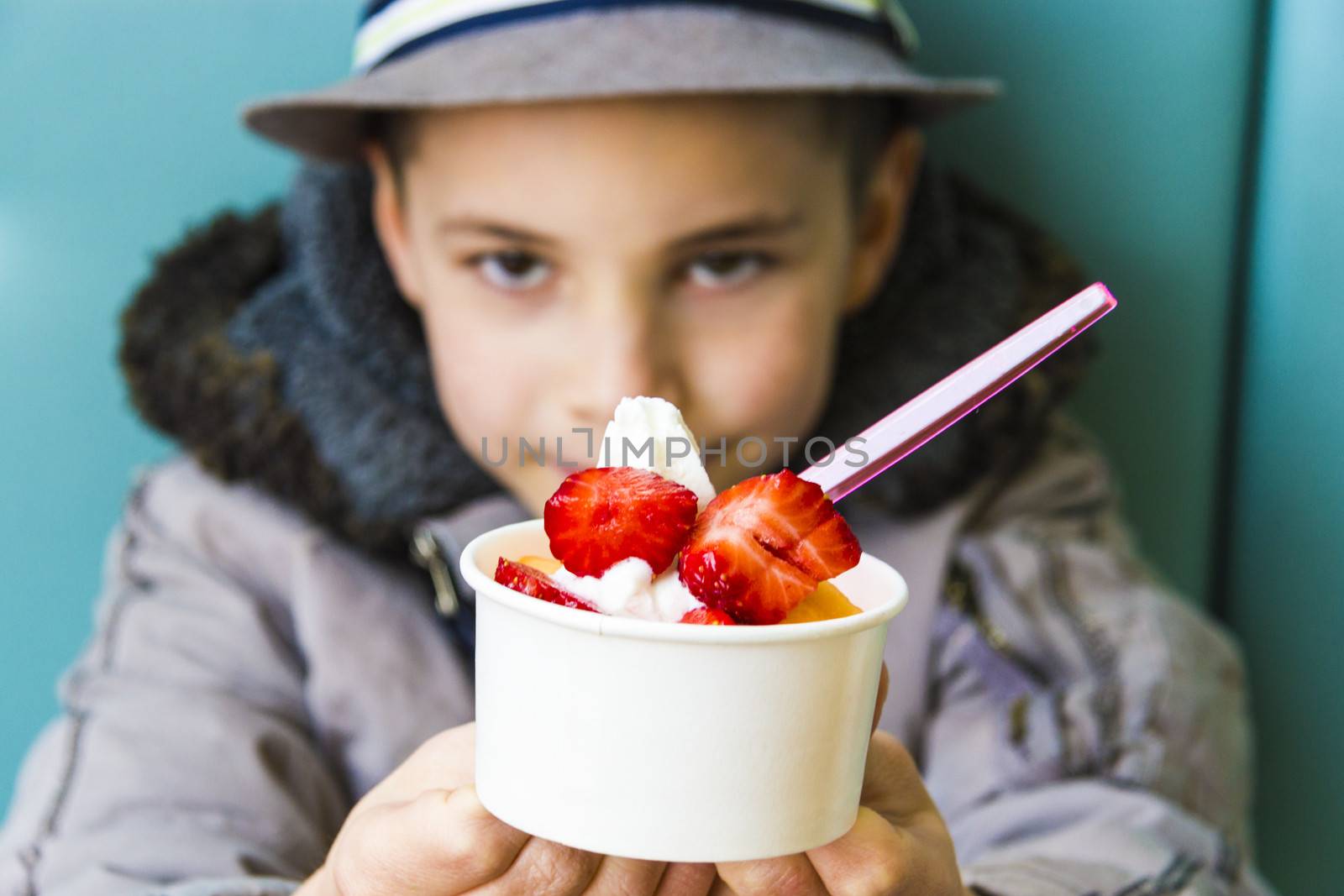 Cute teenage boy offering ice cream with strawberry and melon topping