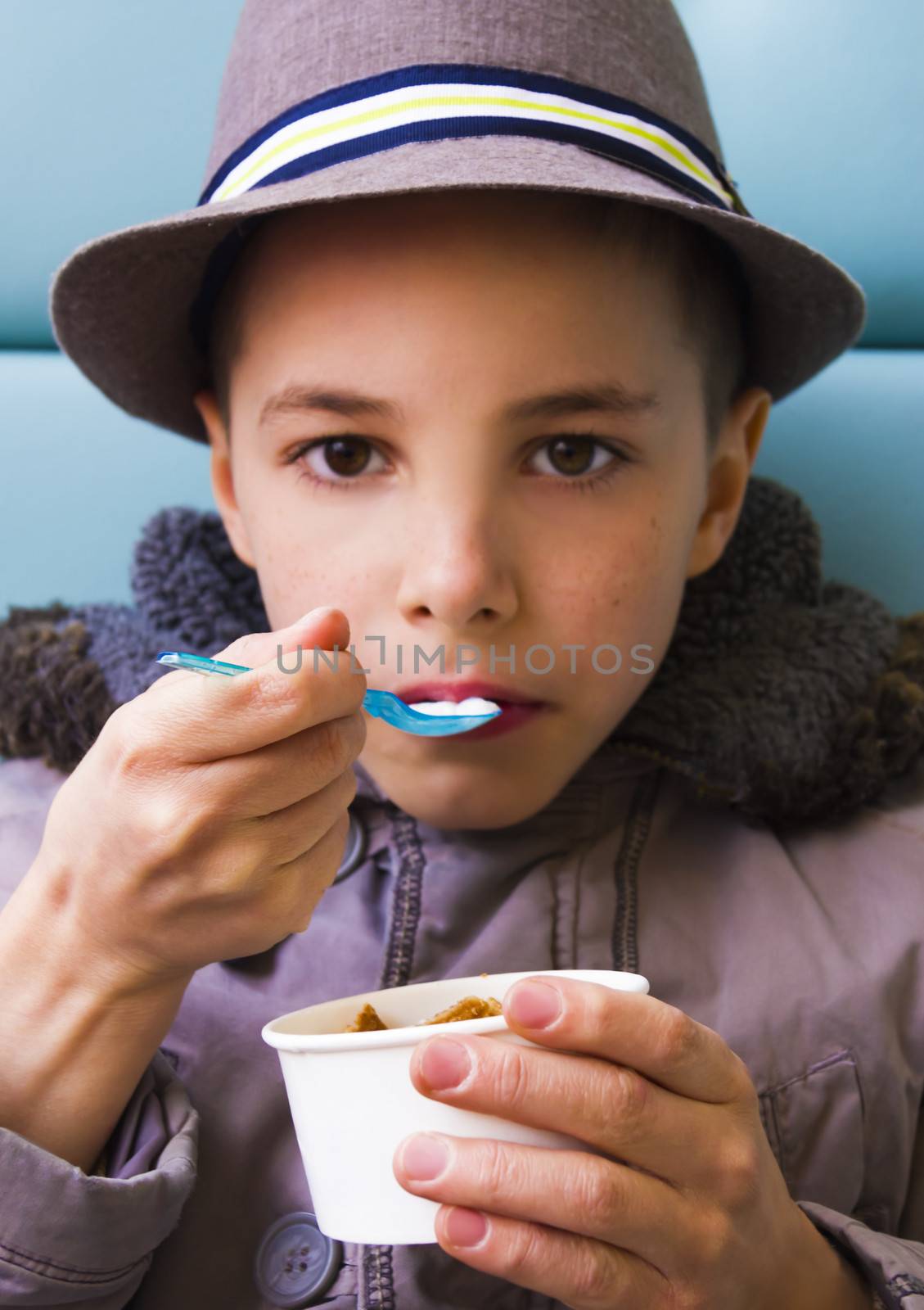 Cute teenage boy eating ice cream with chocolate topping