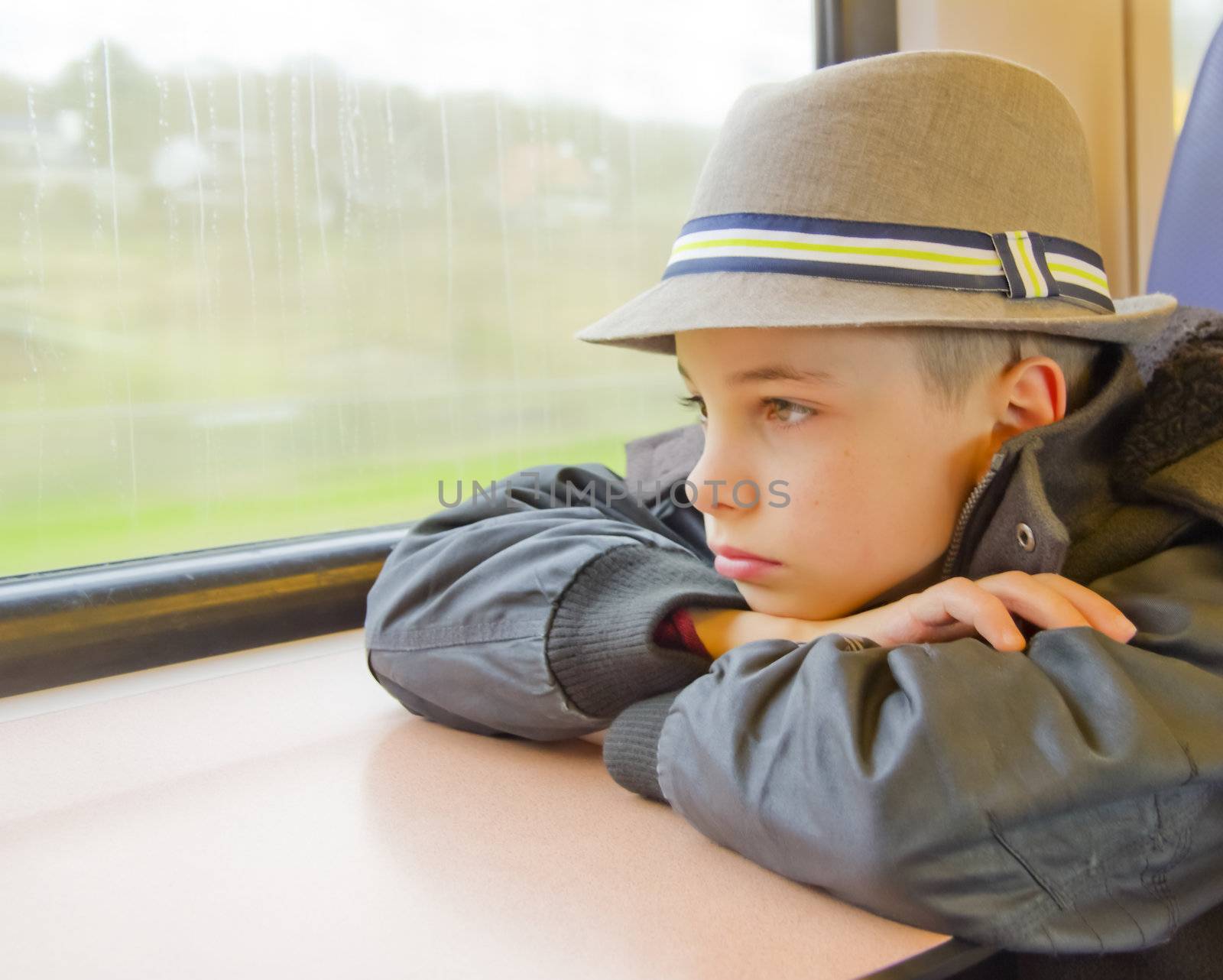 Boy rides on a train and looking out the window. by Tetyana