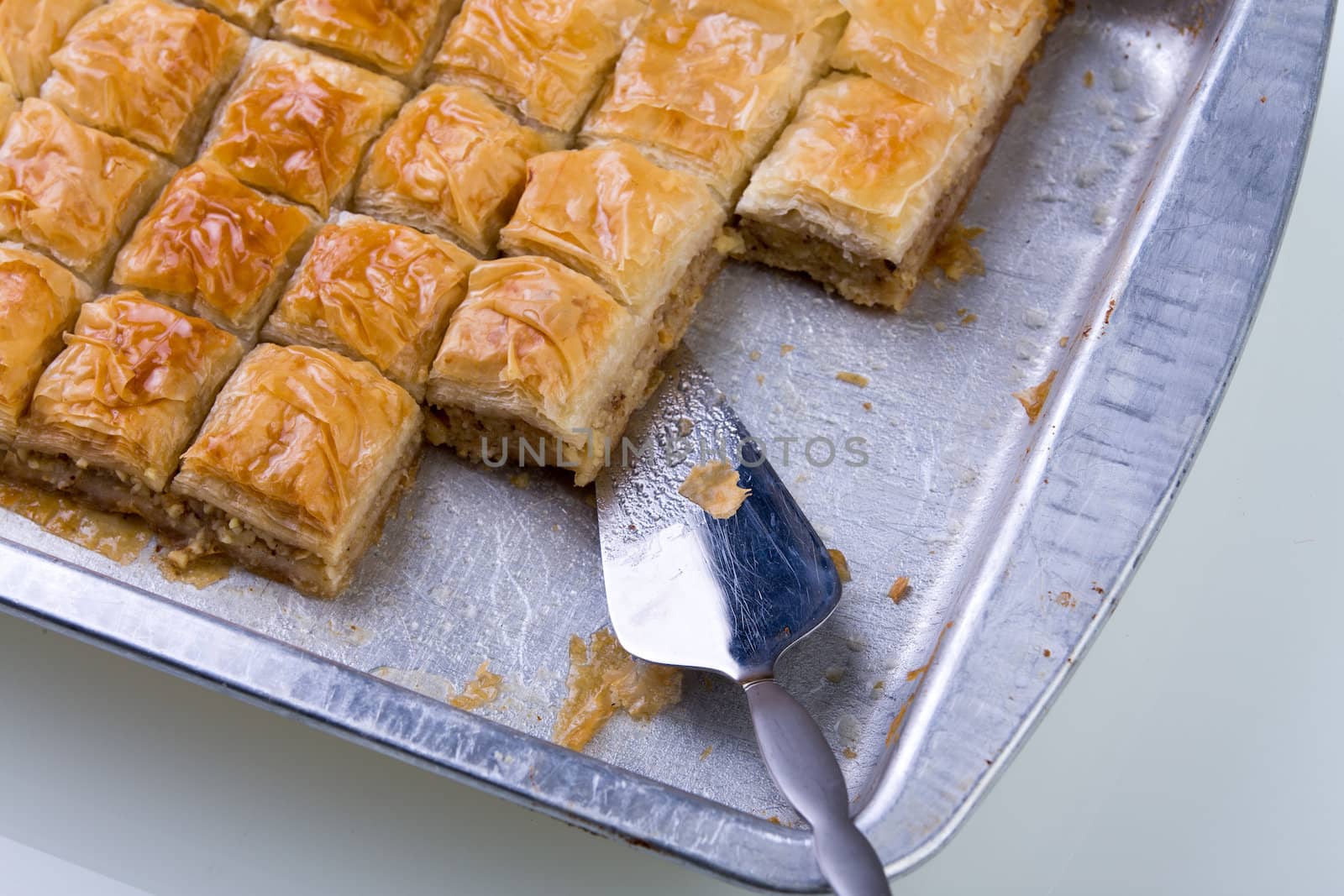 Home made baklava ready to serv from aluminum tray with brushed stailes-steel spatula