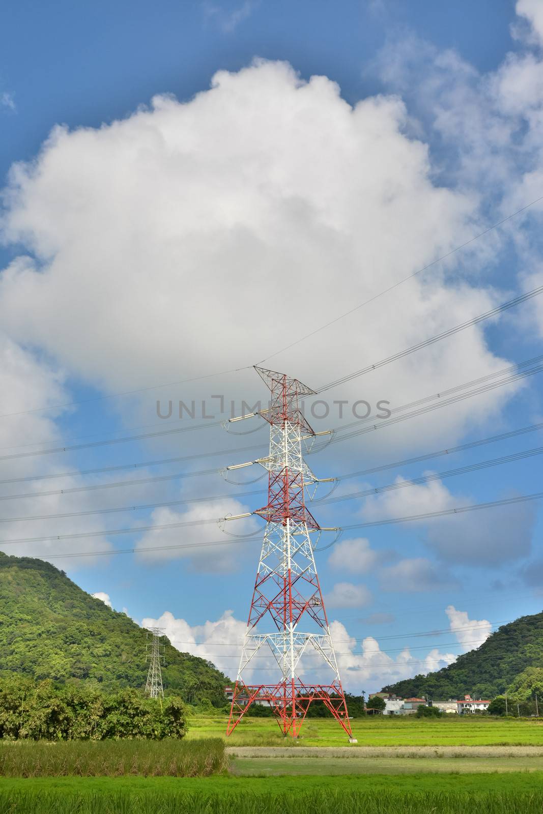 Electronic tower on the meadow under cloudy blue sky.