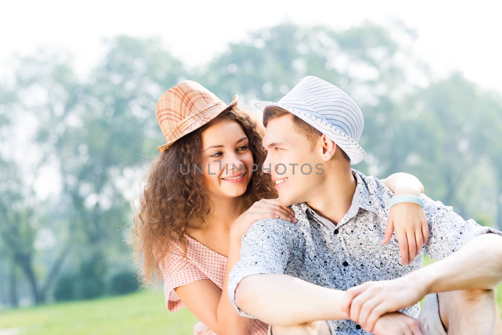 romantic couple lying on the grass in the summer park, spending time with loved ones