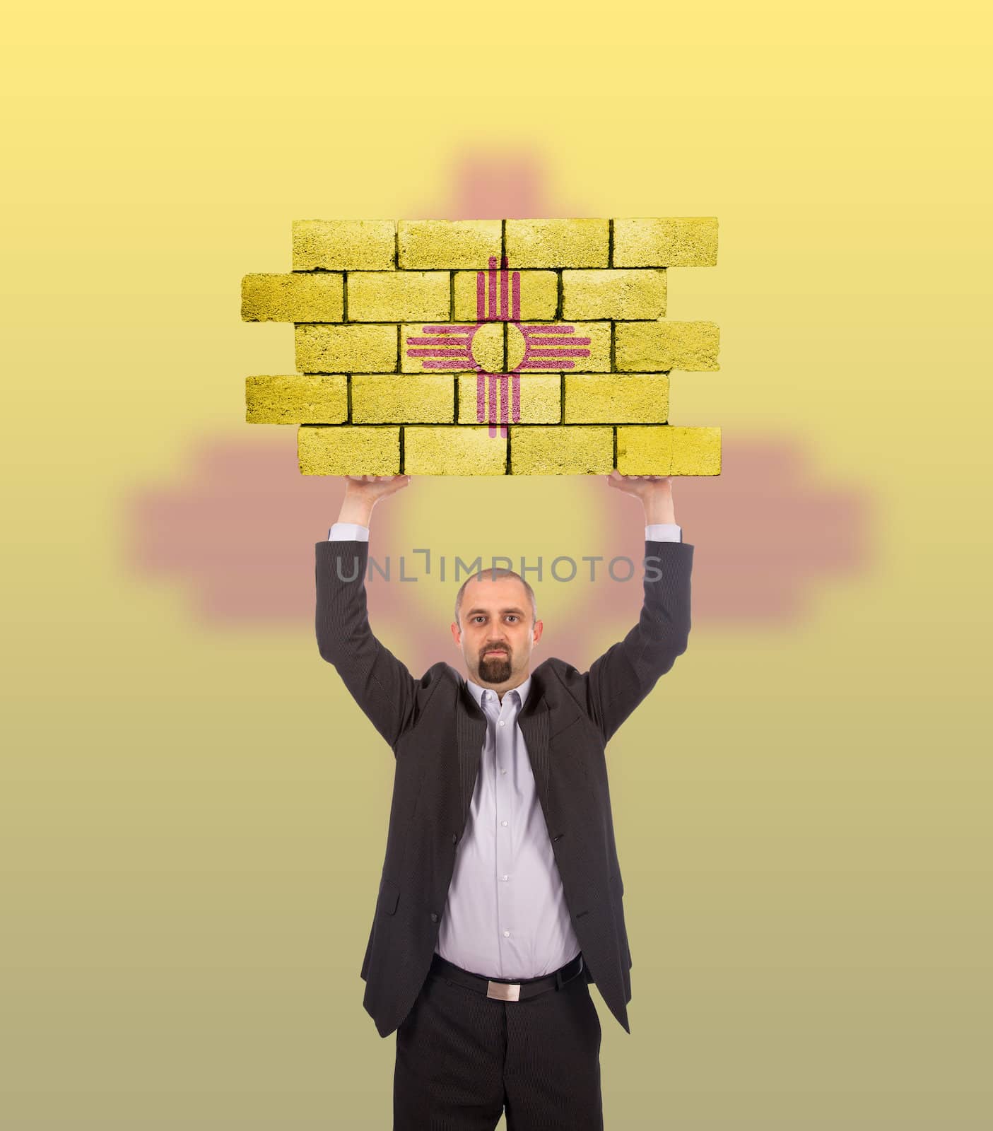 Businessman holding a large piece of a brick wall, flag of New Mexico, isolated on national flag