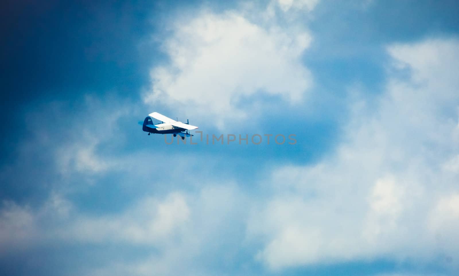 Biplane In Blue Sky Over Clouds