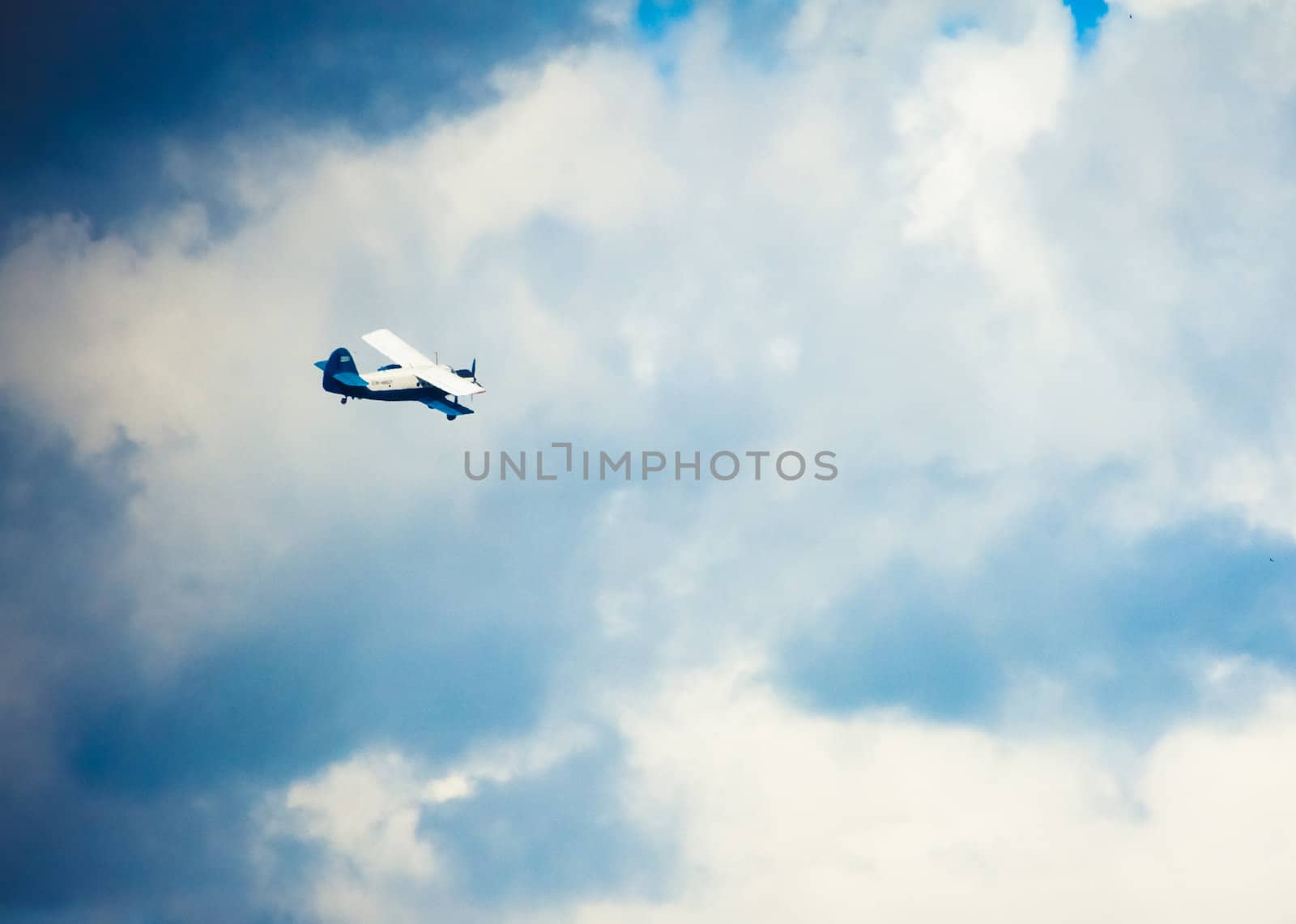 Biplane In Blue Sky Over Clouds