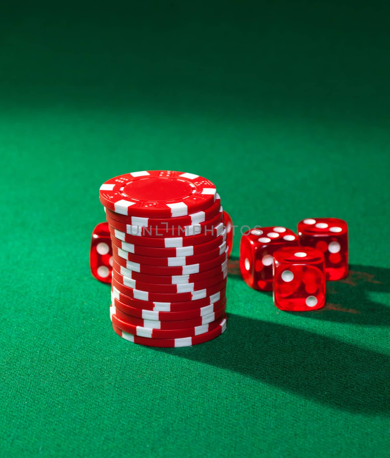 Red poker chips and red dice on green cloth