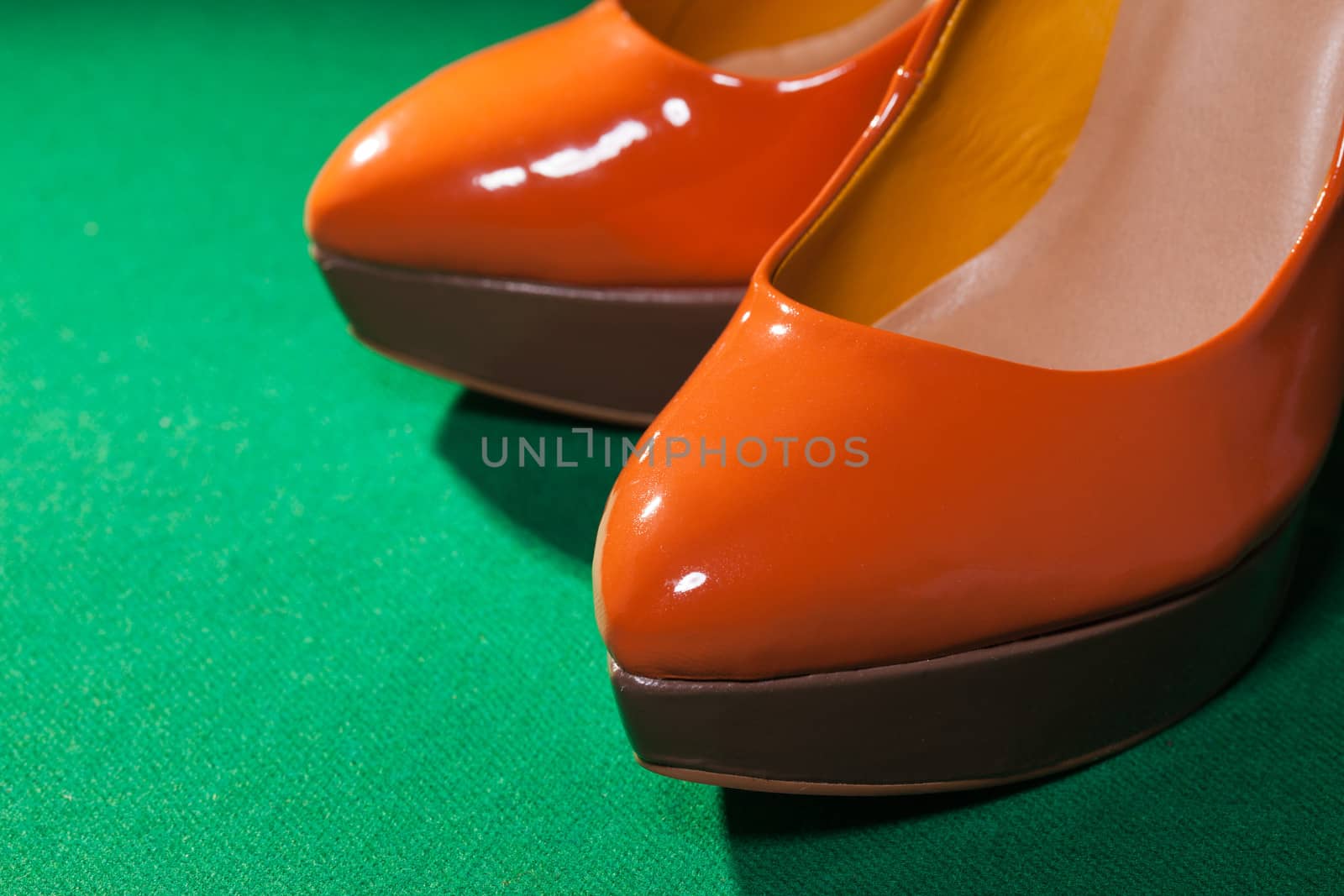 Female orange shoes on green cloth background