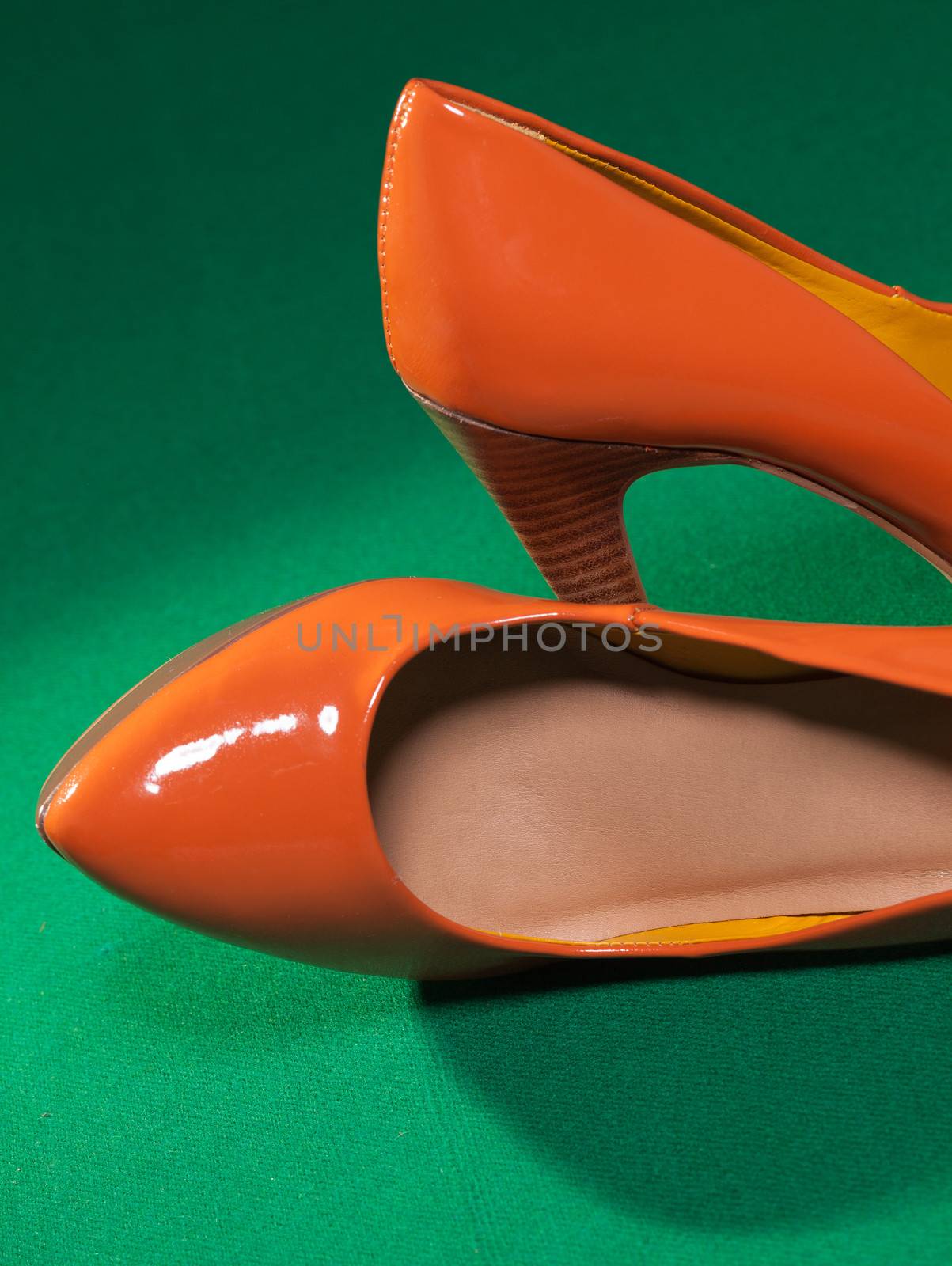 Female orange shoes on green cloth background