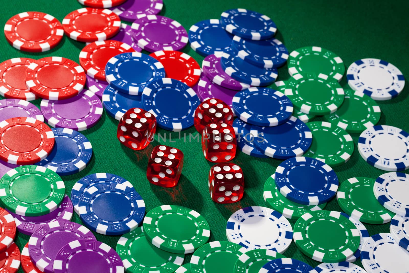 Colorful poker chips and red dice on green cloth