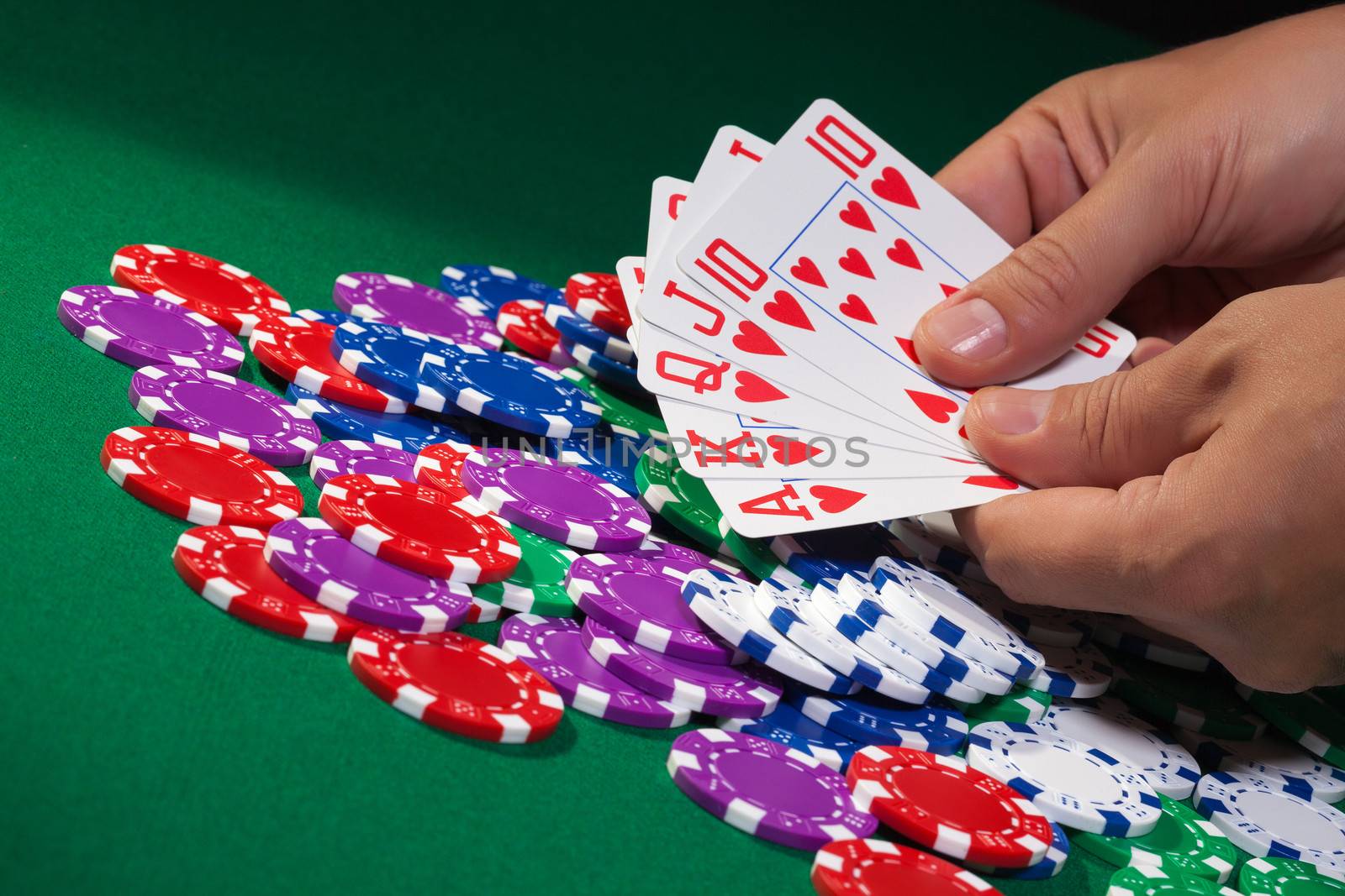 Colorful poker chips and royal flush closeup on green cloth