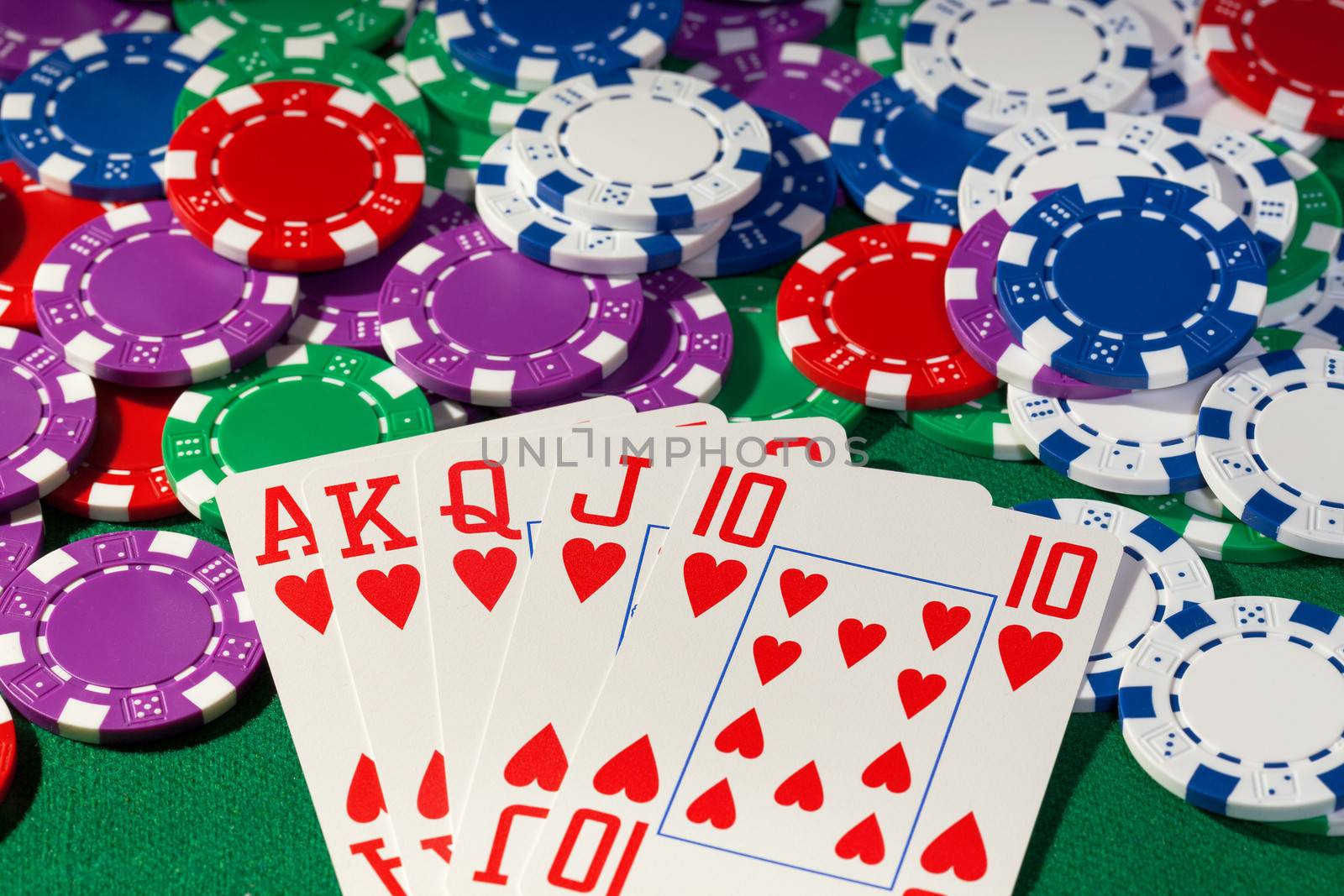 Colorful poker chips and royal flush closeup on green cloth